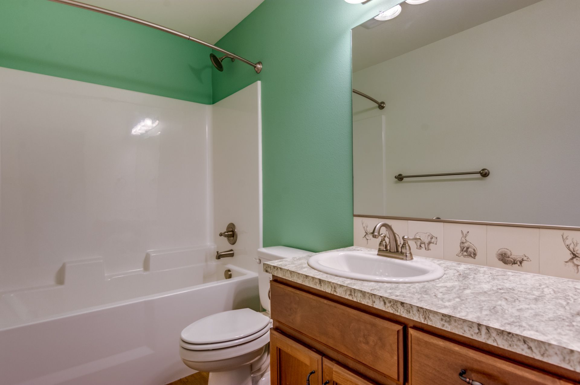 A bathroom with a toilet , sink , bathtub and mirror.
