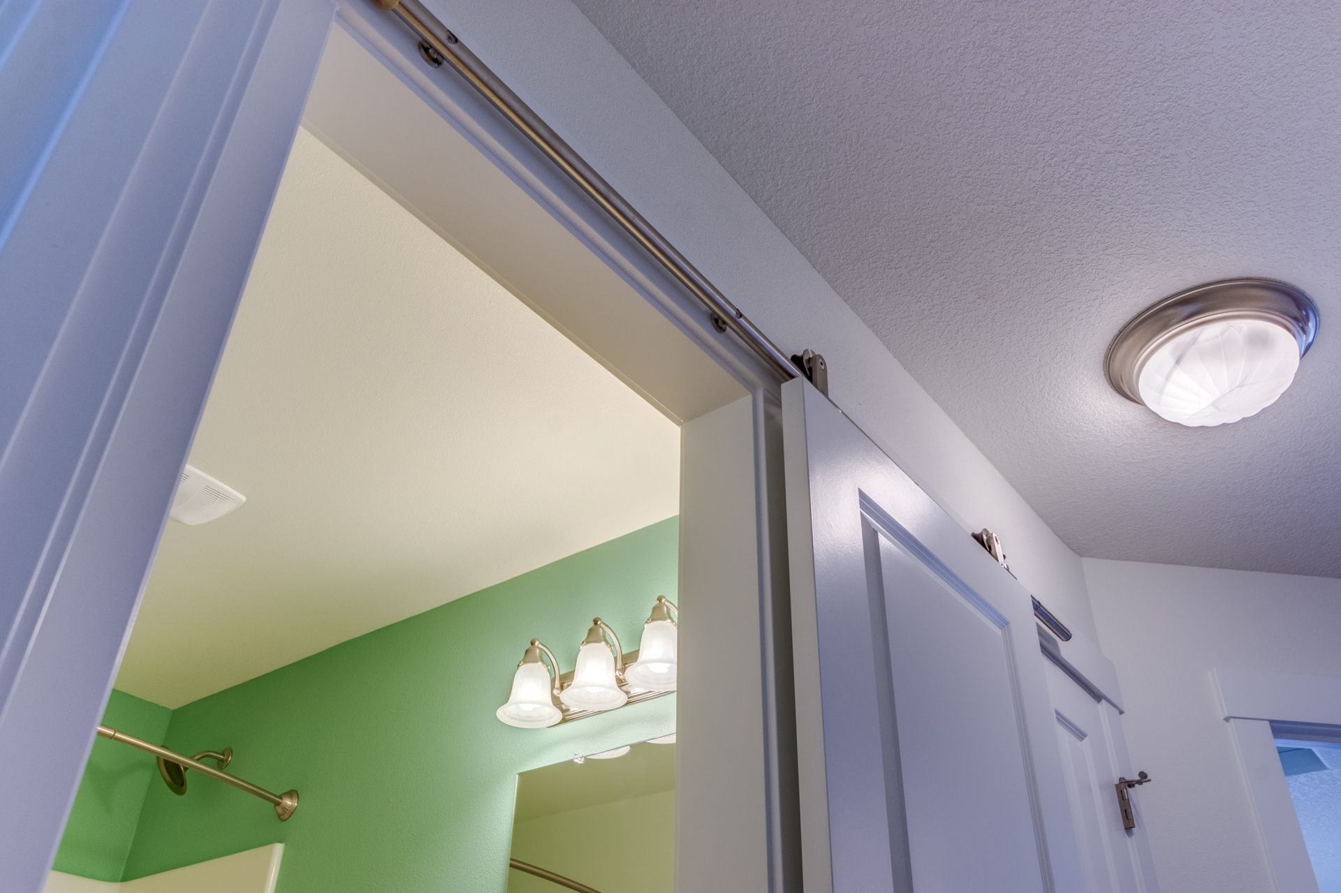 A bathroom with green walls and a sliding door leading to it.