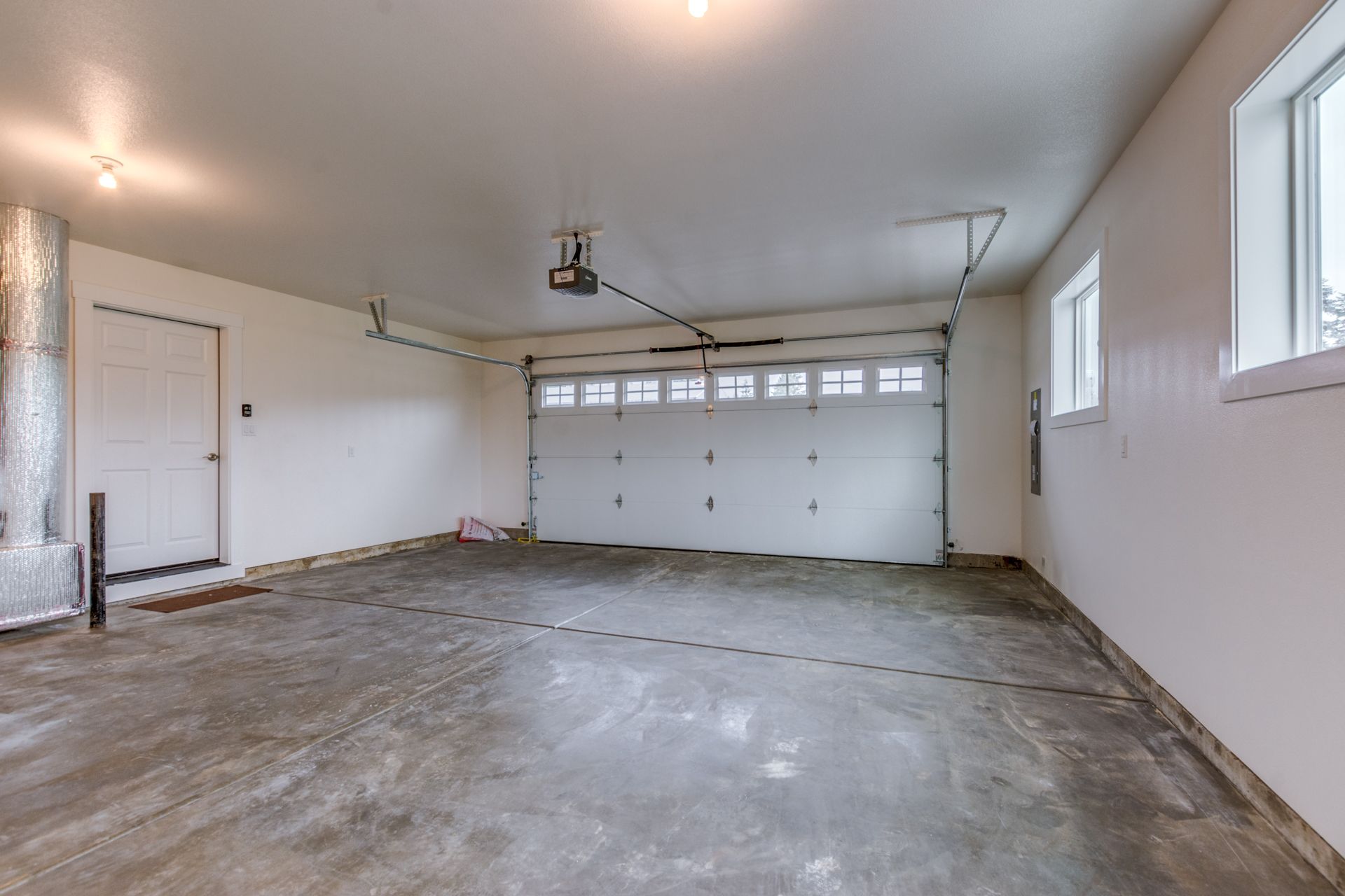 An empty garage with a garage door open and a window.