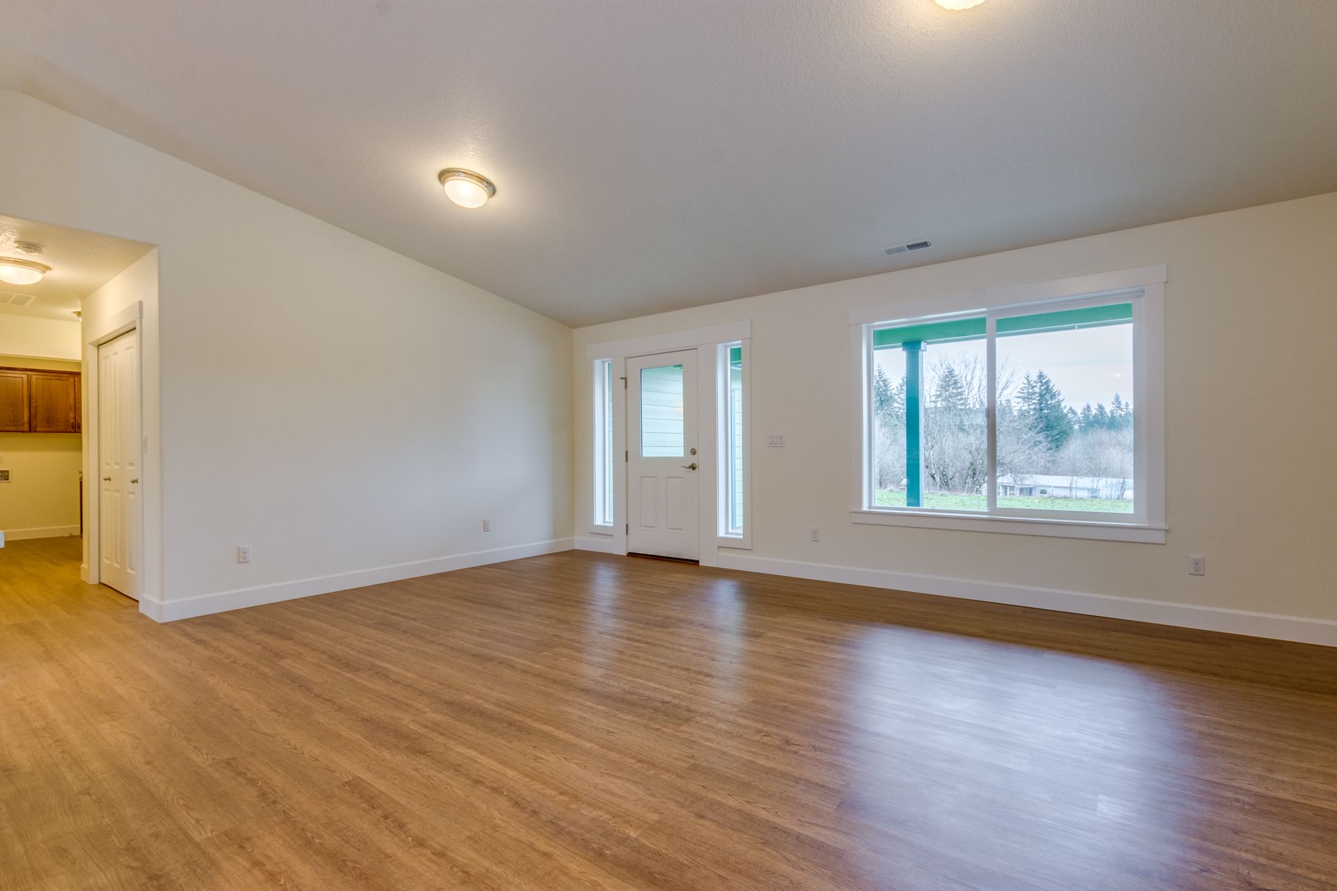 An empty living room with hardwood floors and white walls.