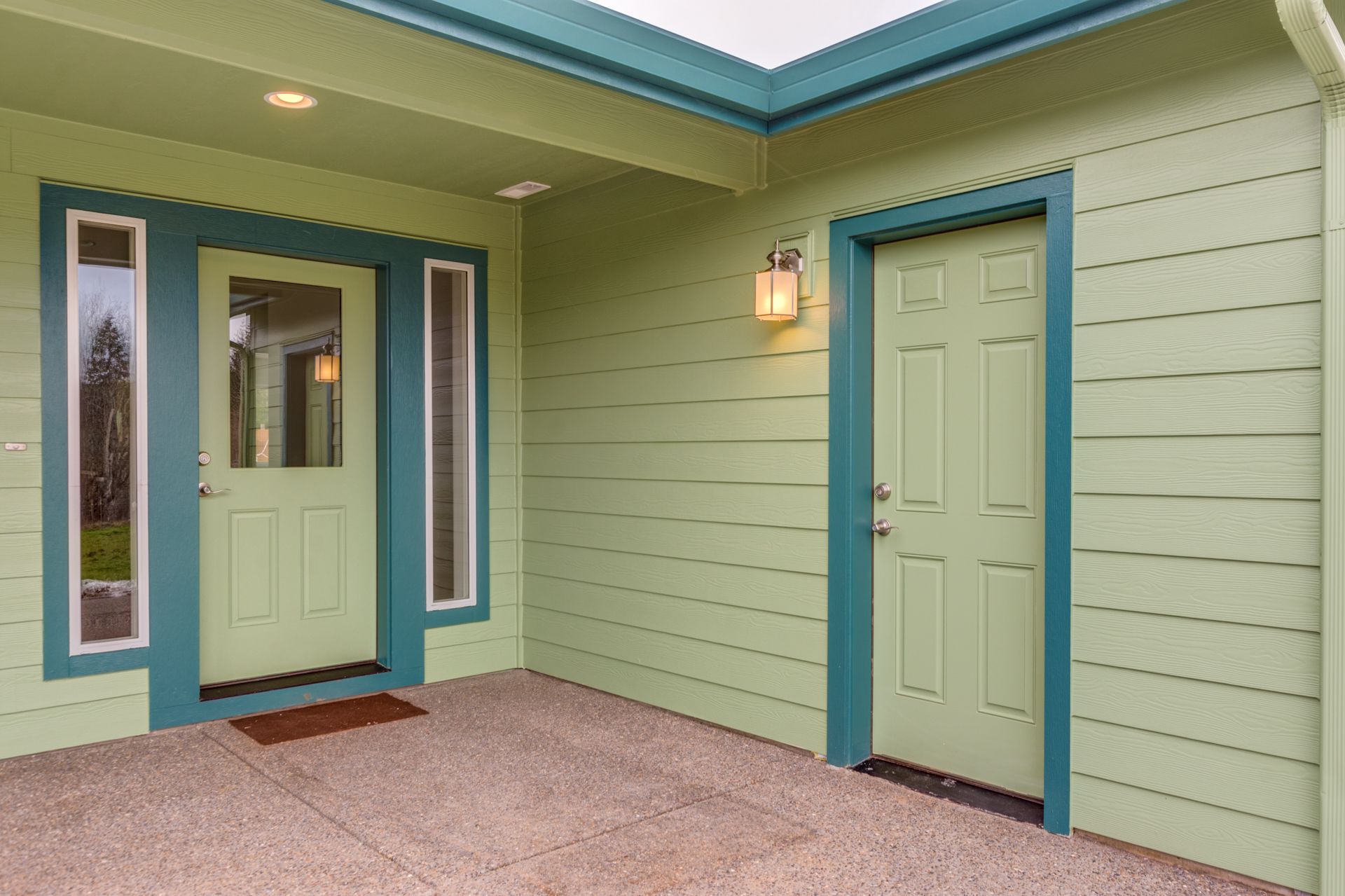 The front door of a house with green siding and blue trim.