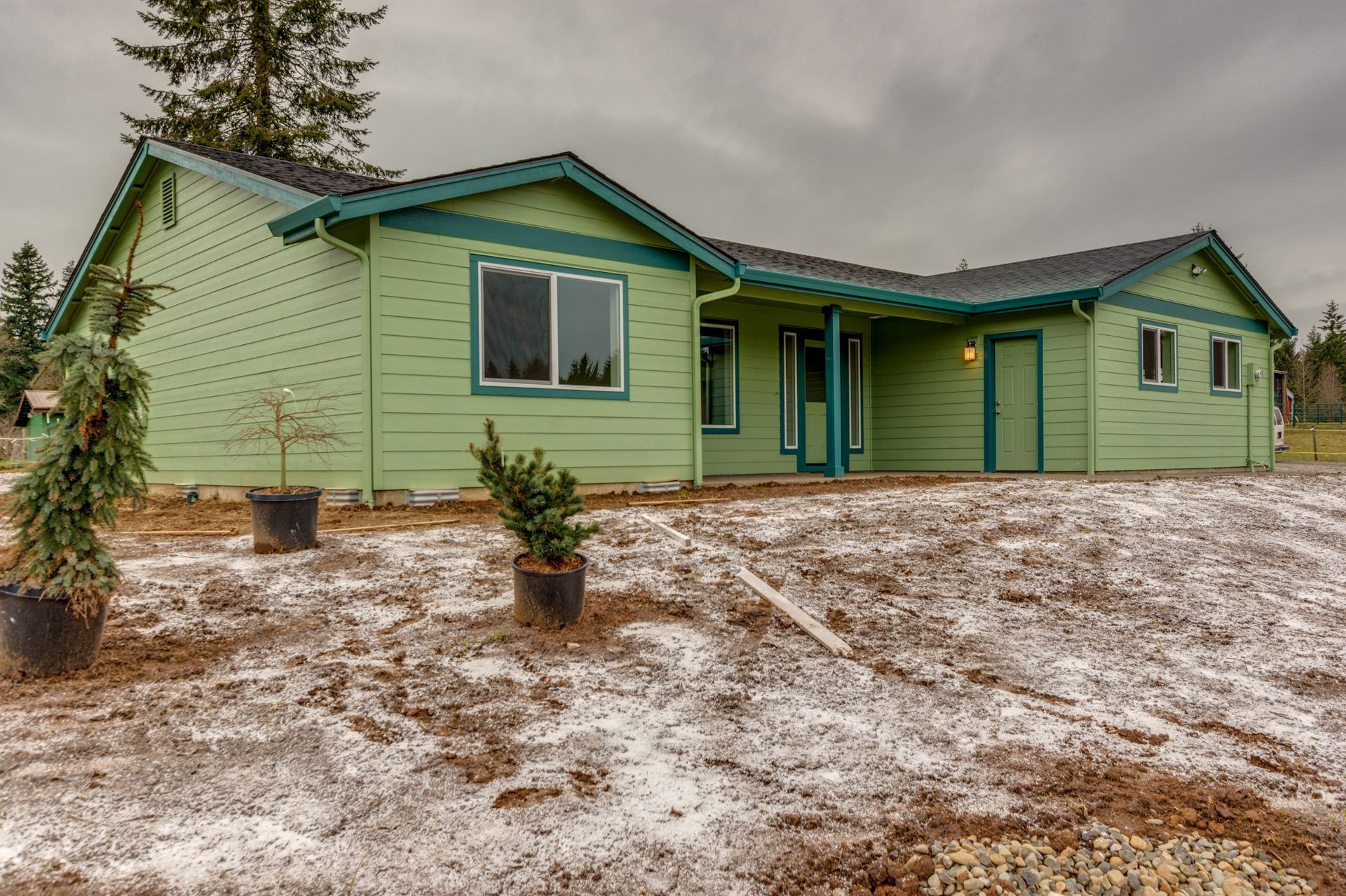 A green house with potted plants in front of it