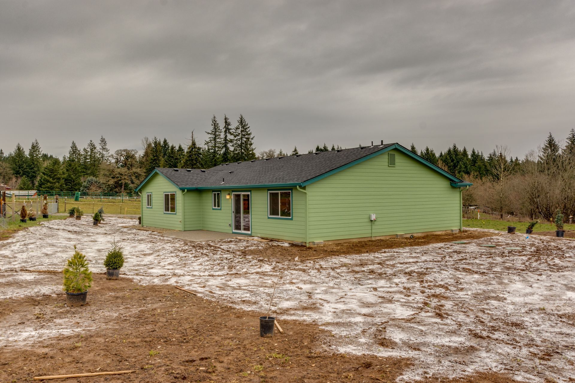 A green house is sitting in the middle of a muddy field.