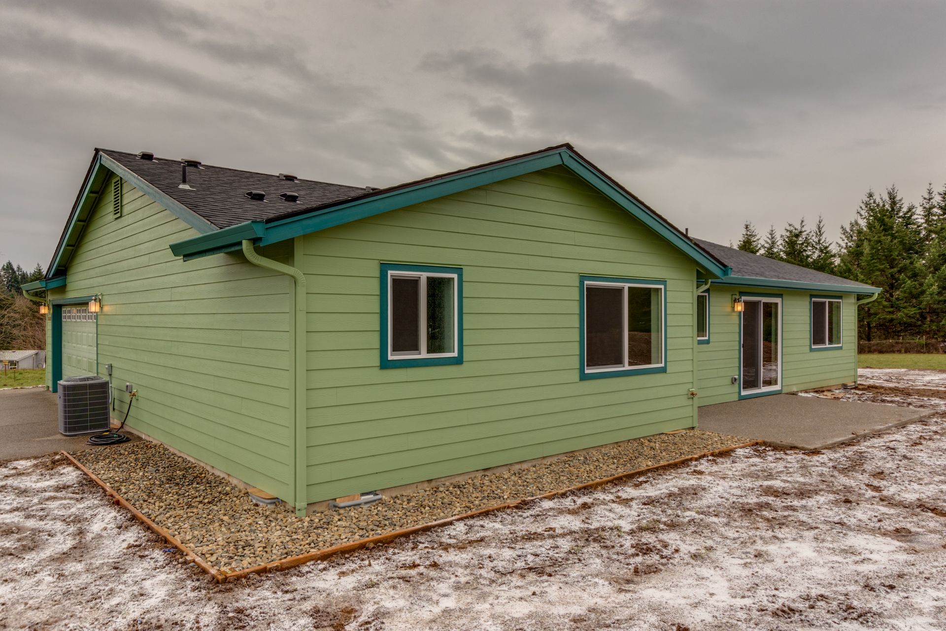 A green house with a black roof is sitting in the middle of a snowy field.