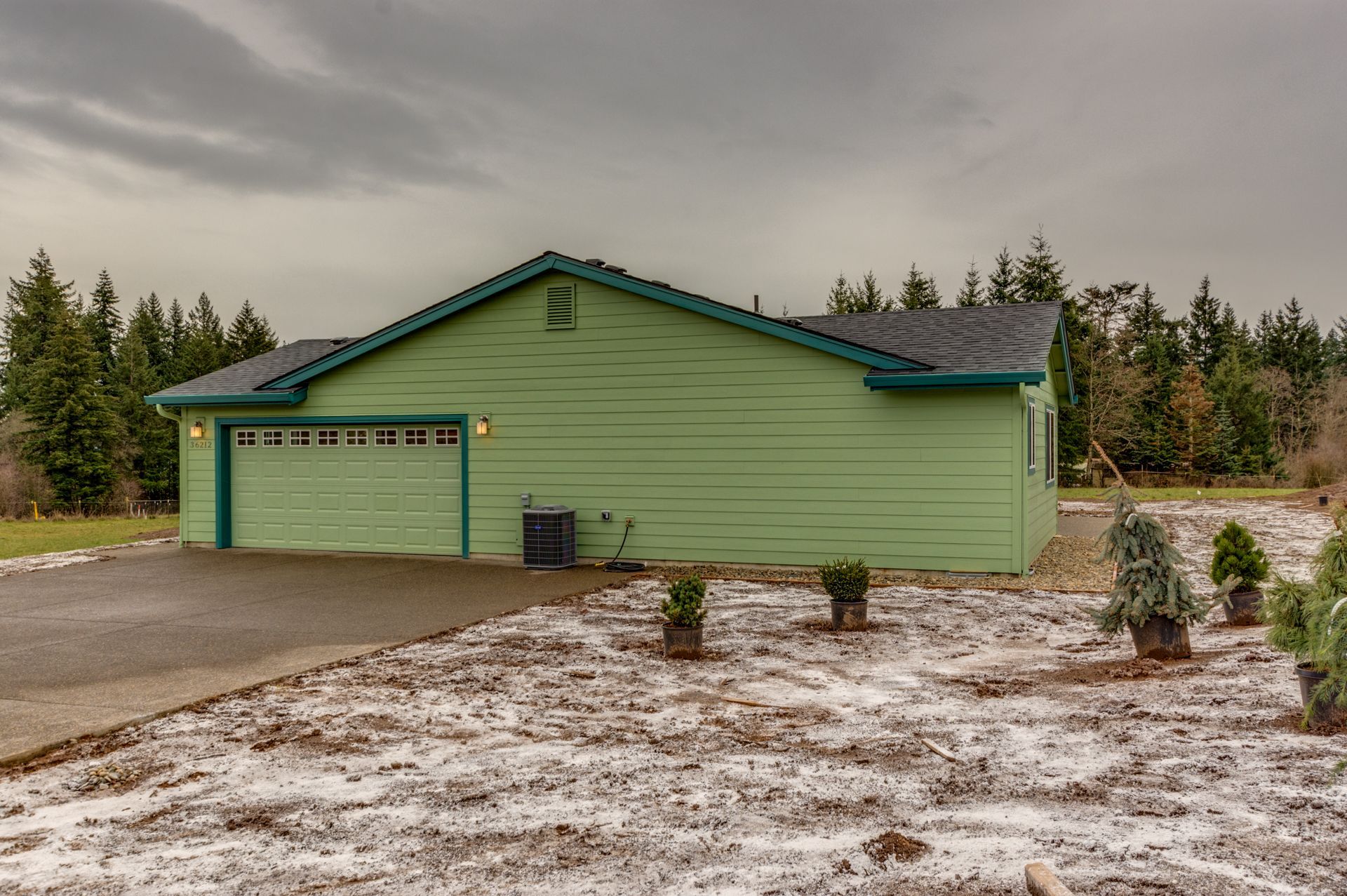 A green house with a garage and a driveway