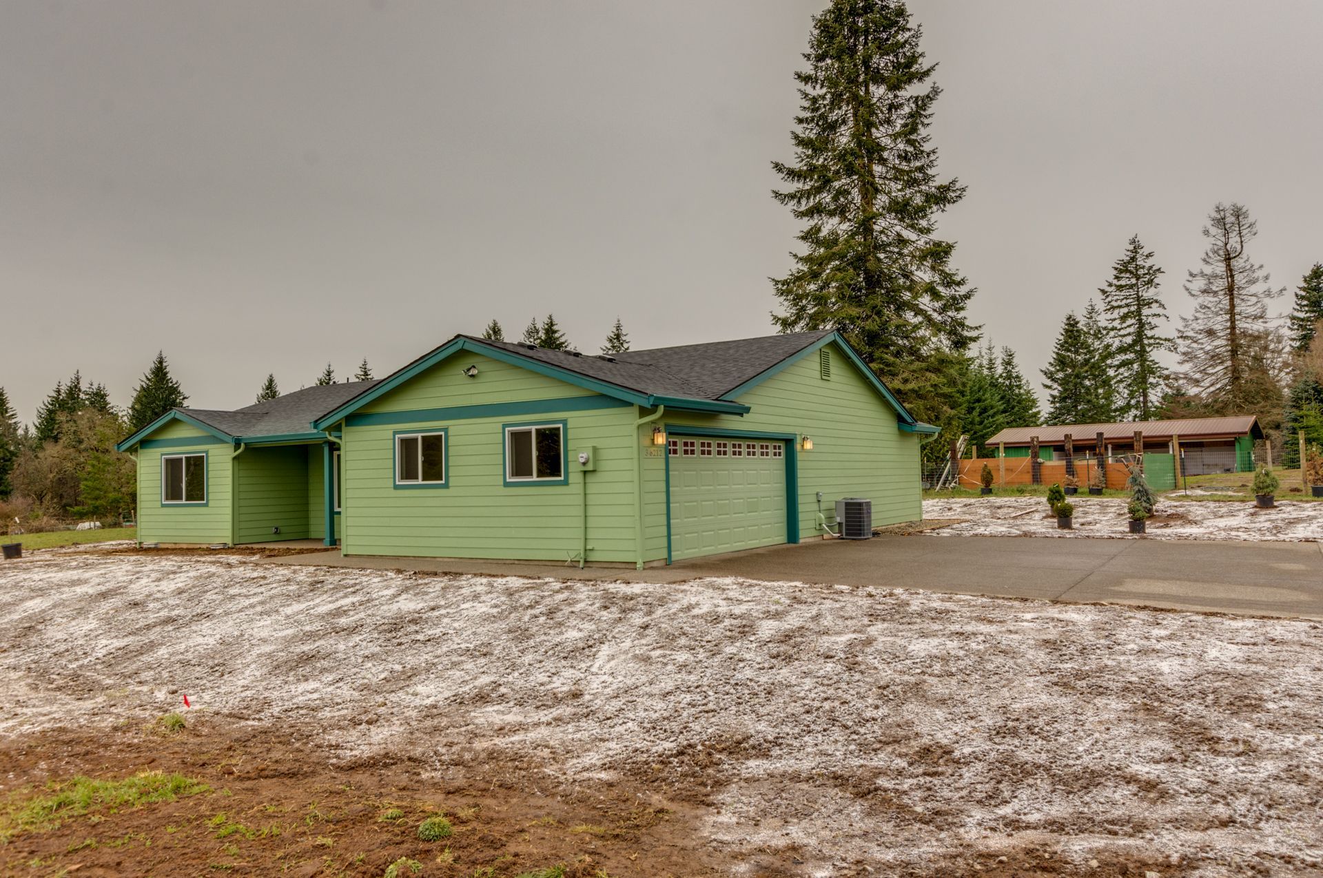 A green house is sitting in the middle of a snowy field.