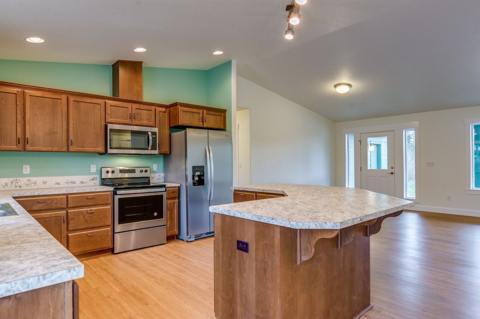 A kitchen with stainless steel appliances , wooden cabinets , granite counter tops and a large island.