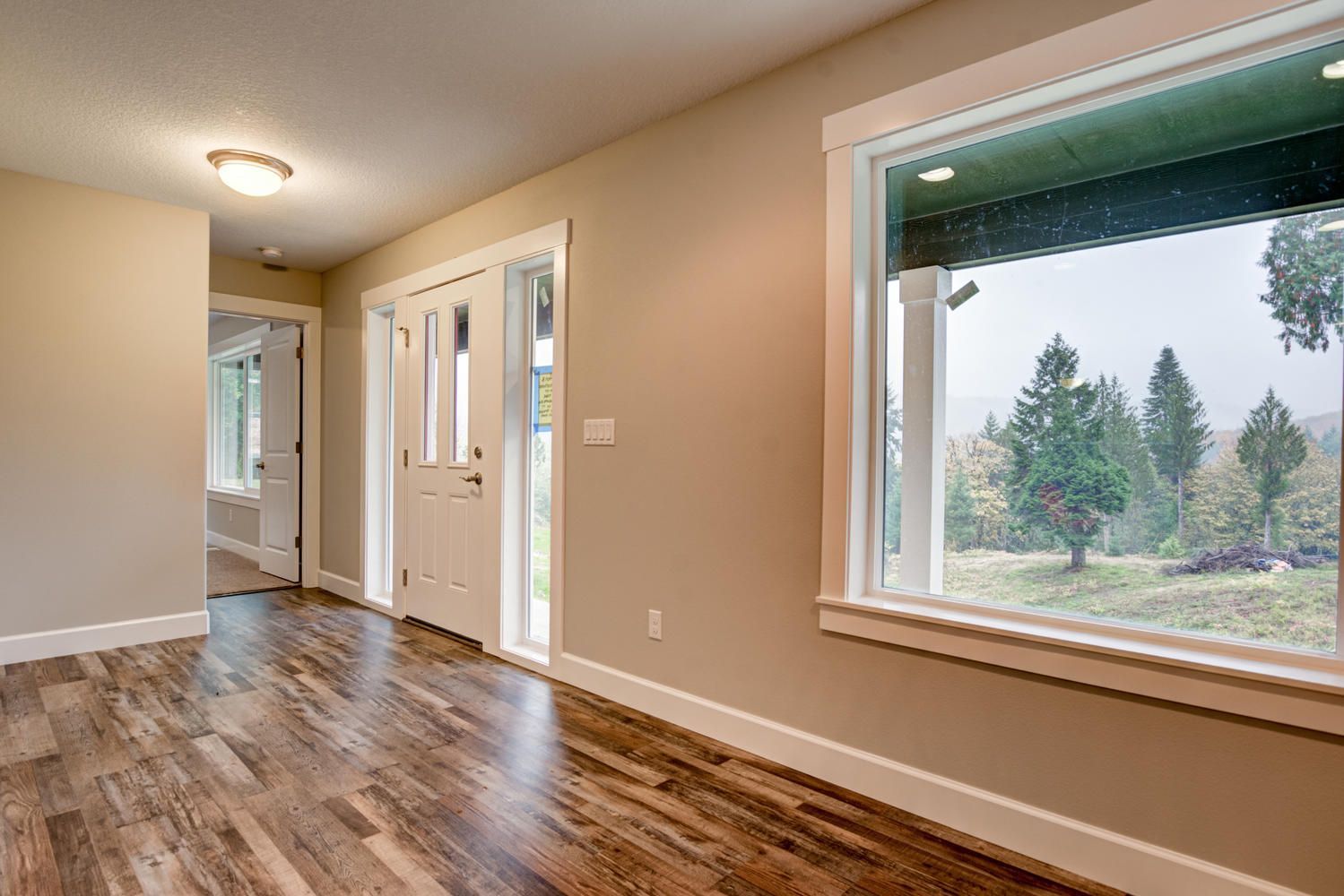 An empty room with hardwood floors and a large window.