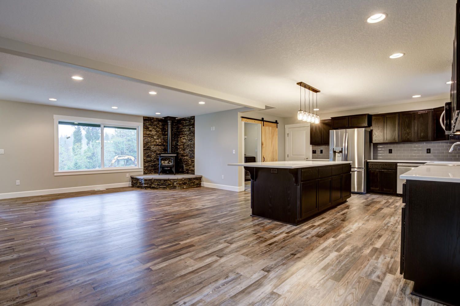 A kitchen and living room in a house with hardwood floors and stainless steel appliances.