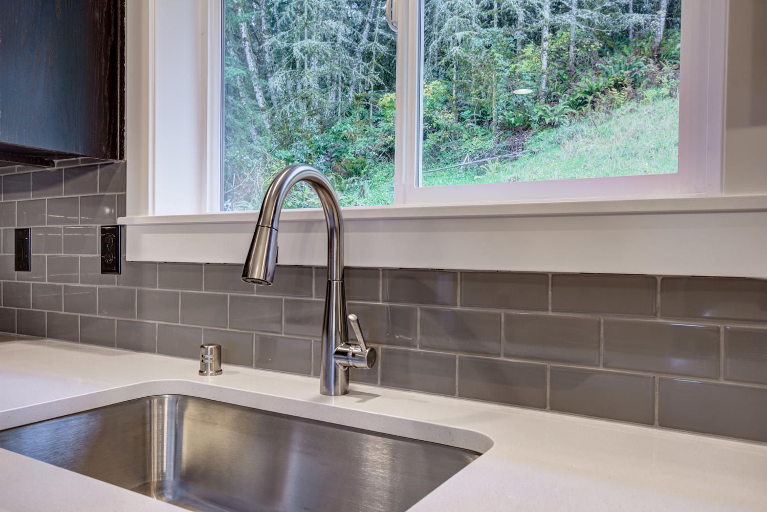 A kitchen sink with a faucet and a window above it.