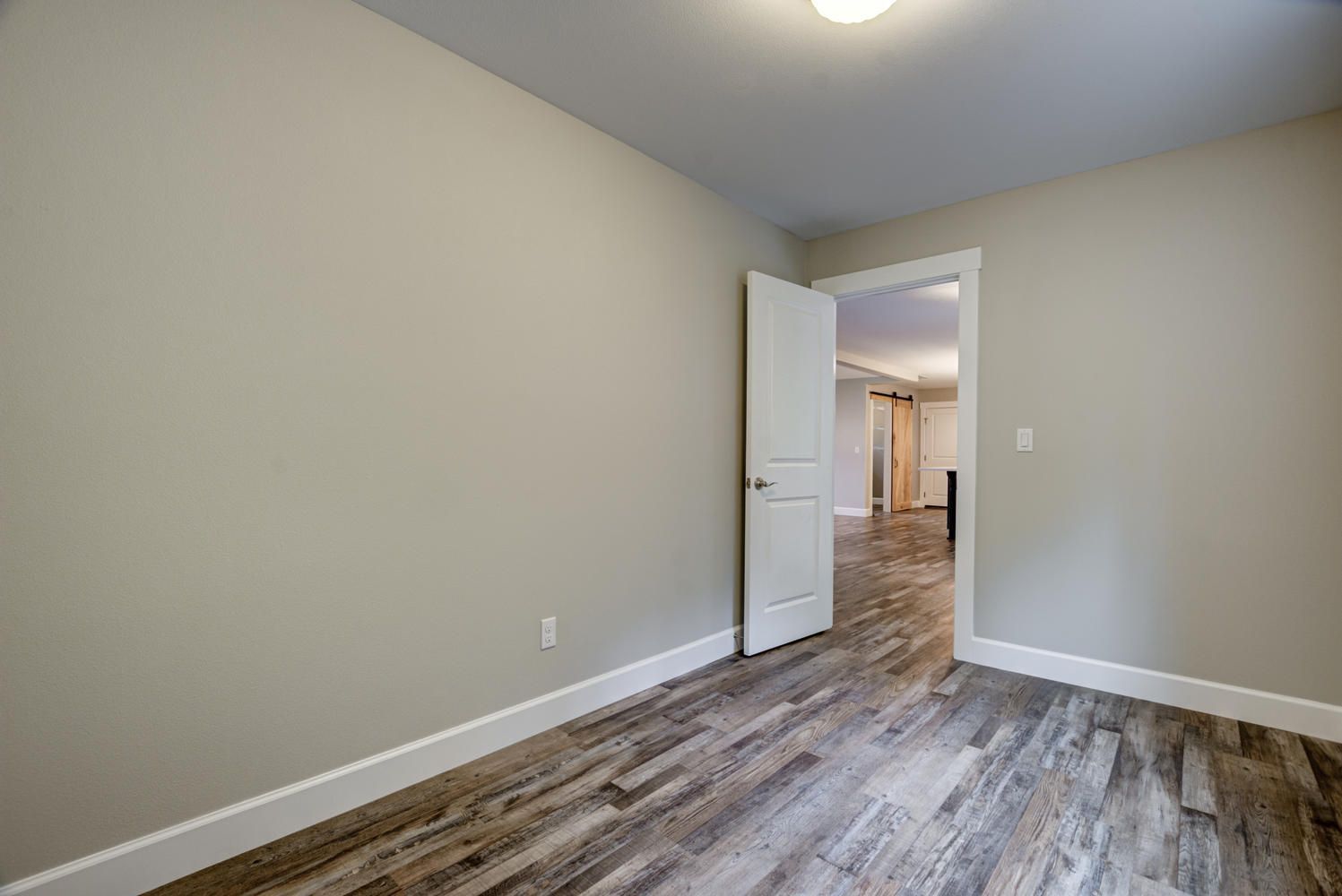An empty room with a wooden floor and a white door.