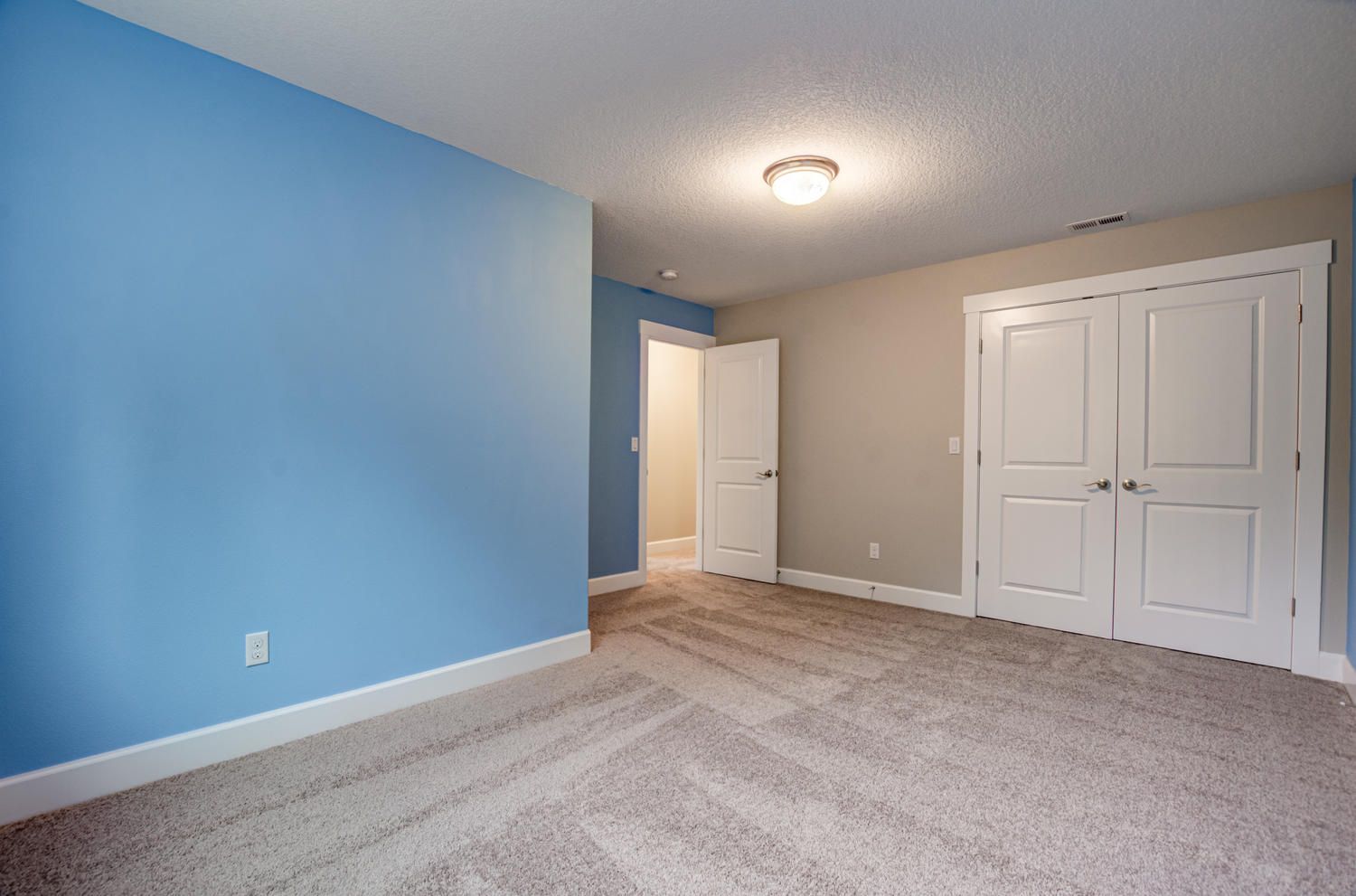 An empty bedroom with blue walls and a carpeted floor.