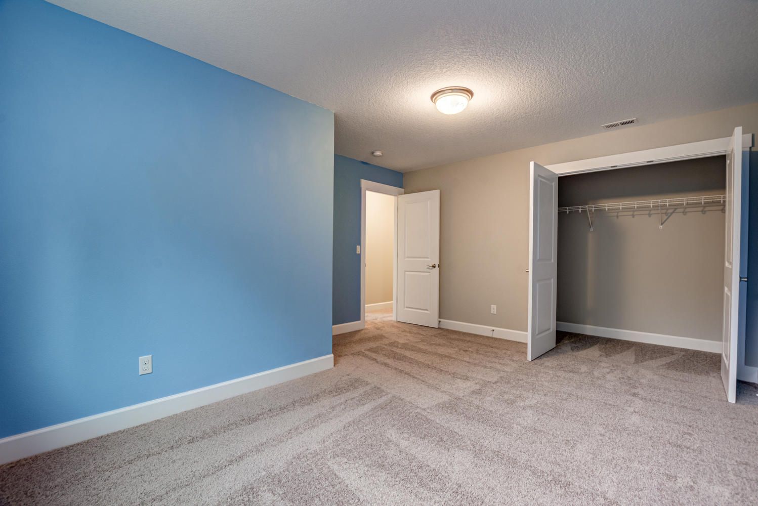An empty bedroom with blue walls and a closet.