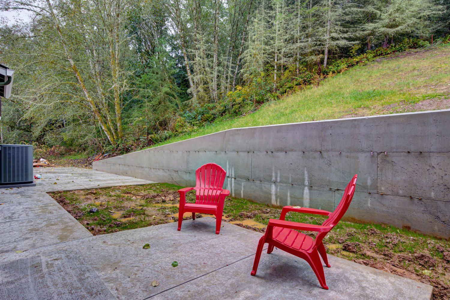 Two red chairs are sitting on a patio next to a concrete wall.