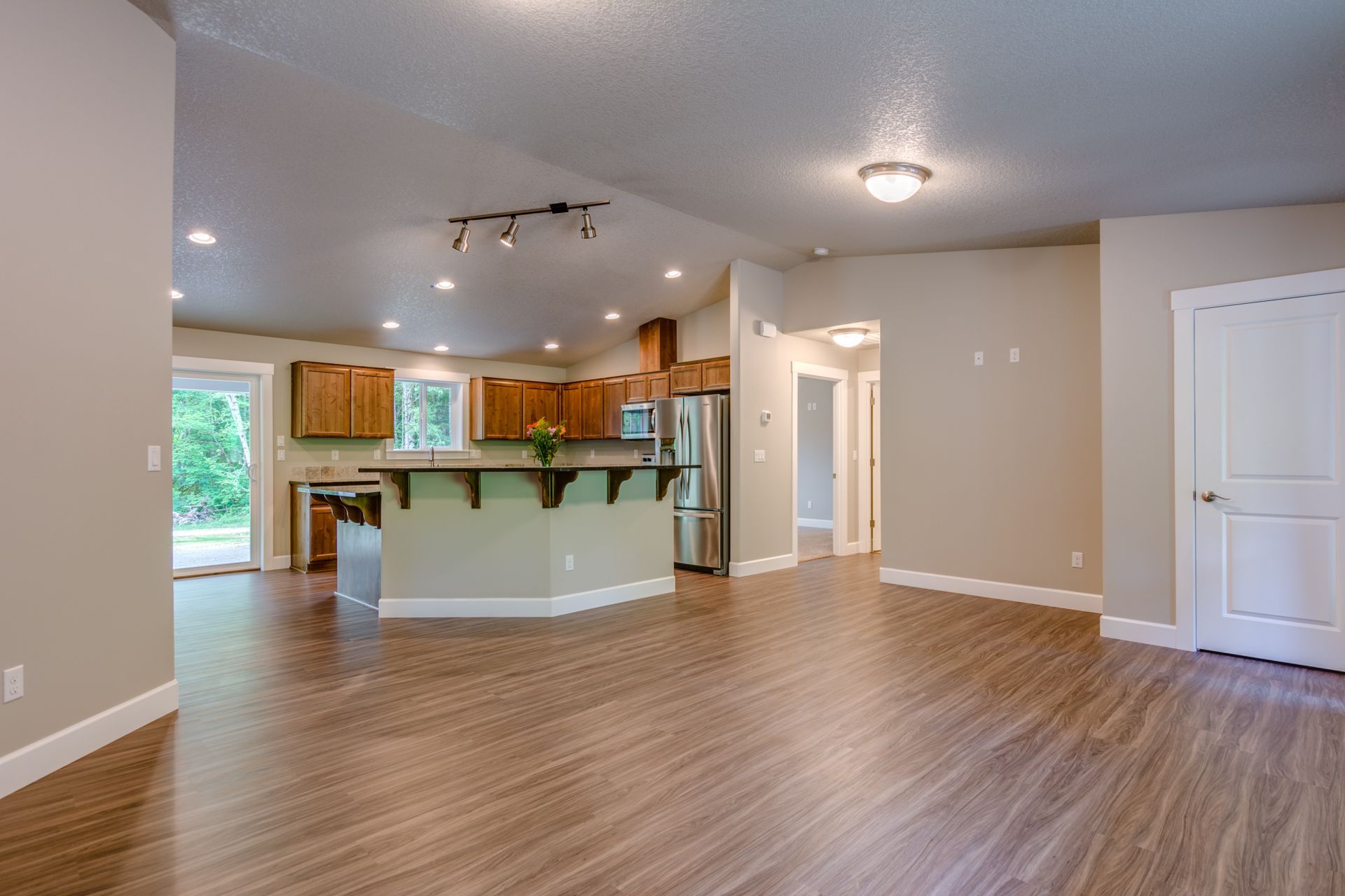 A living room with hardwood floors and a kitchen in the background.