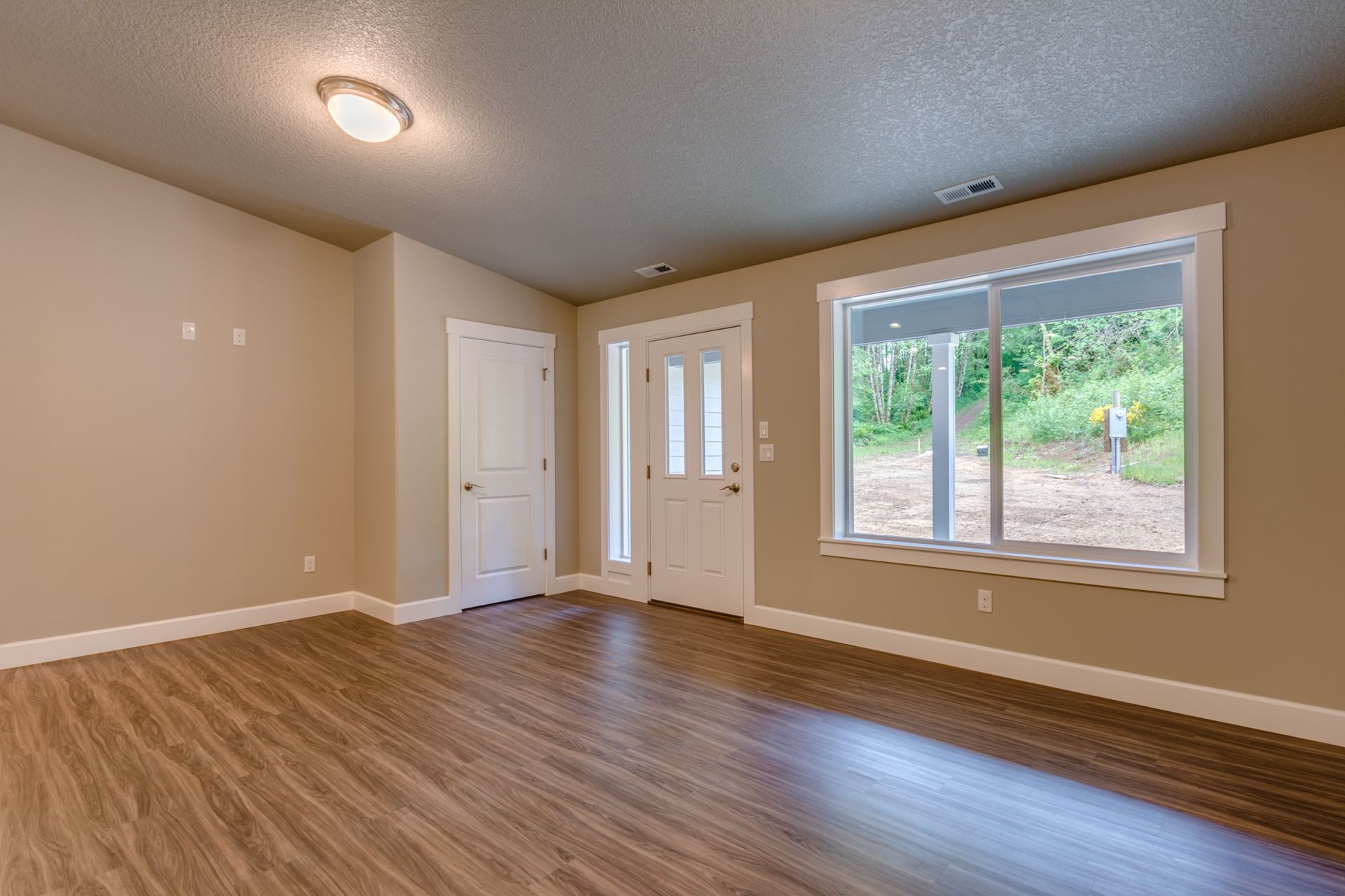 An empty living room with hardwood floors and two windows.