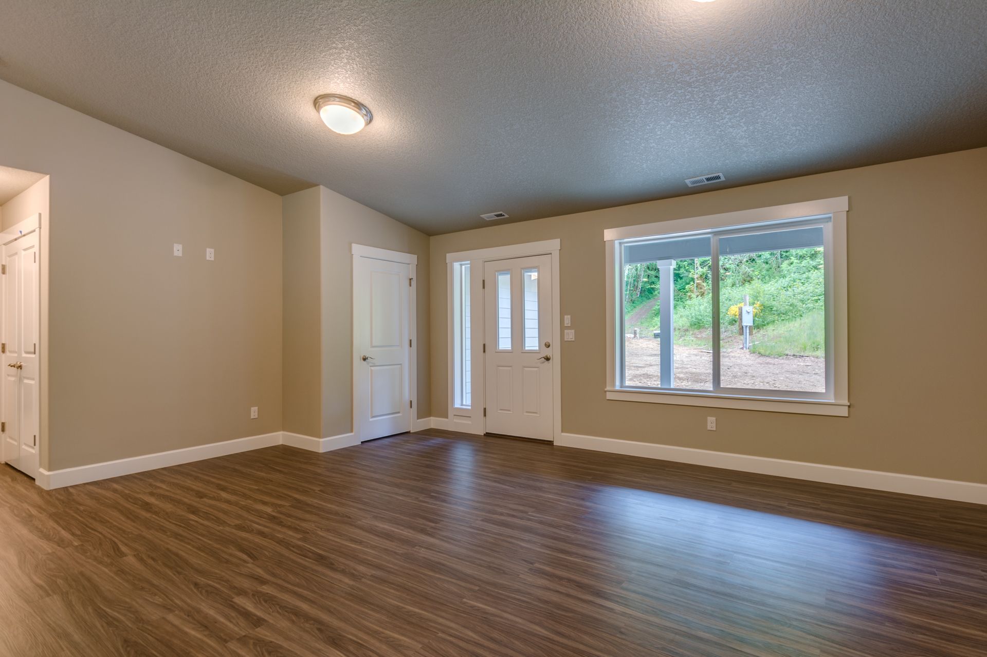 An empty living room with hardwood floors and two windows.