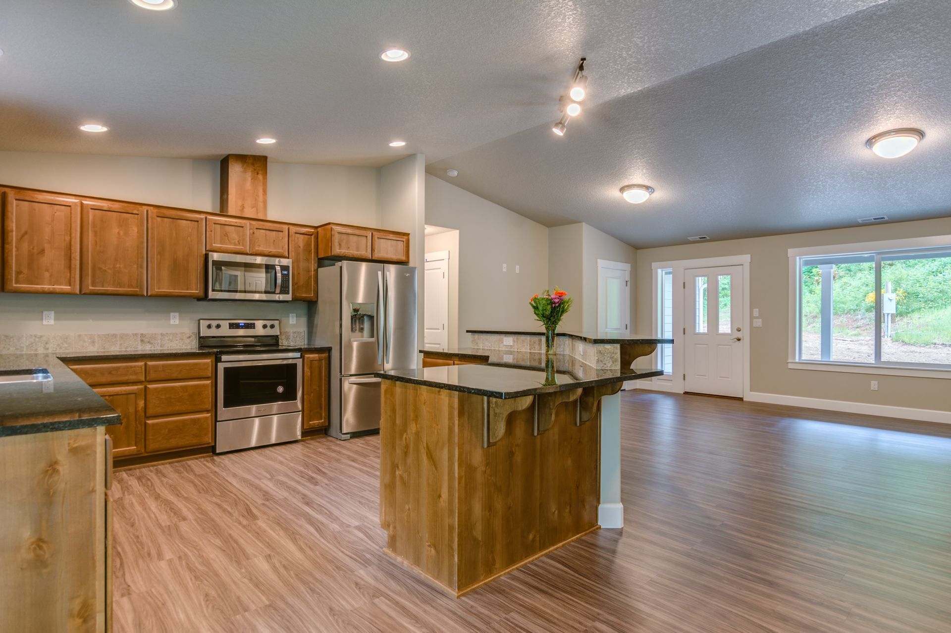 A kitchen with wooden cabinets , stainless steel appliances , and a large island.