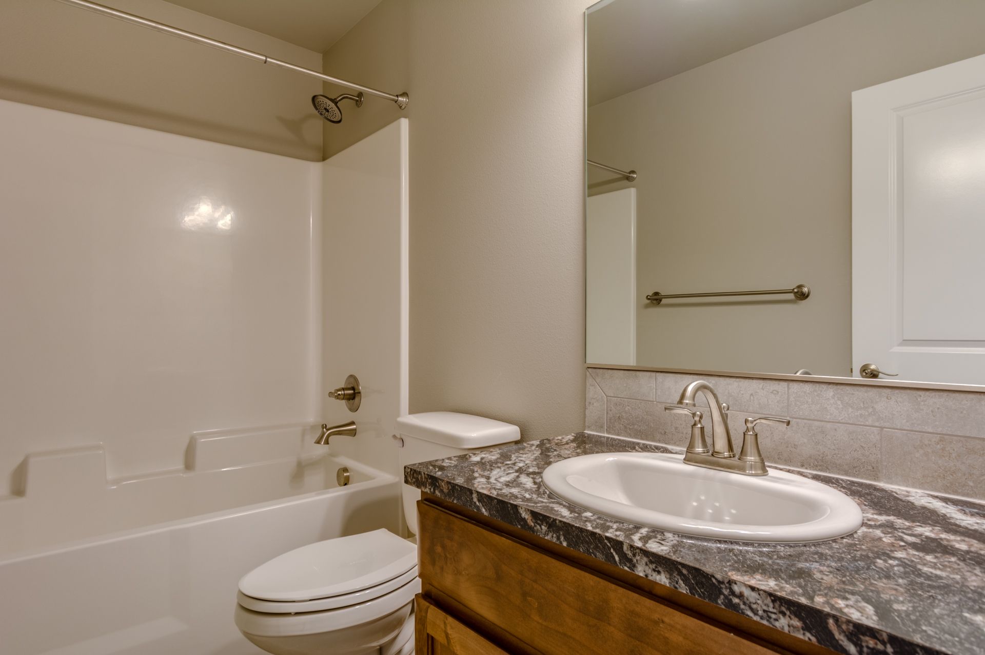 A bathroom with a toilet , sink , bathtub and mirror.