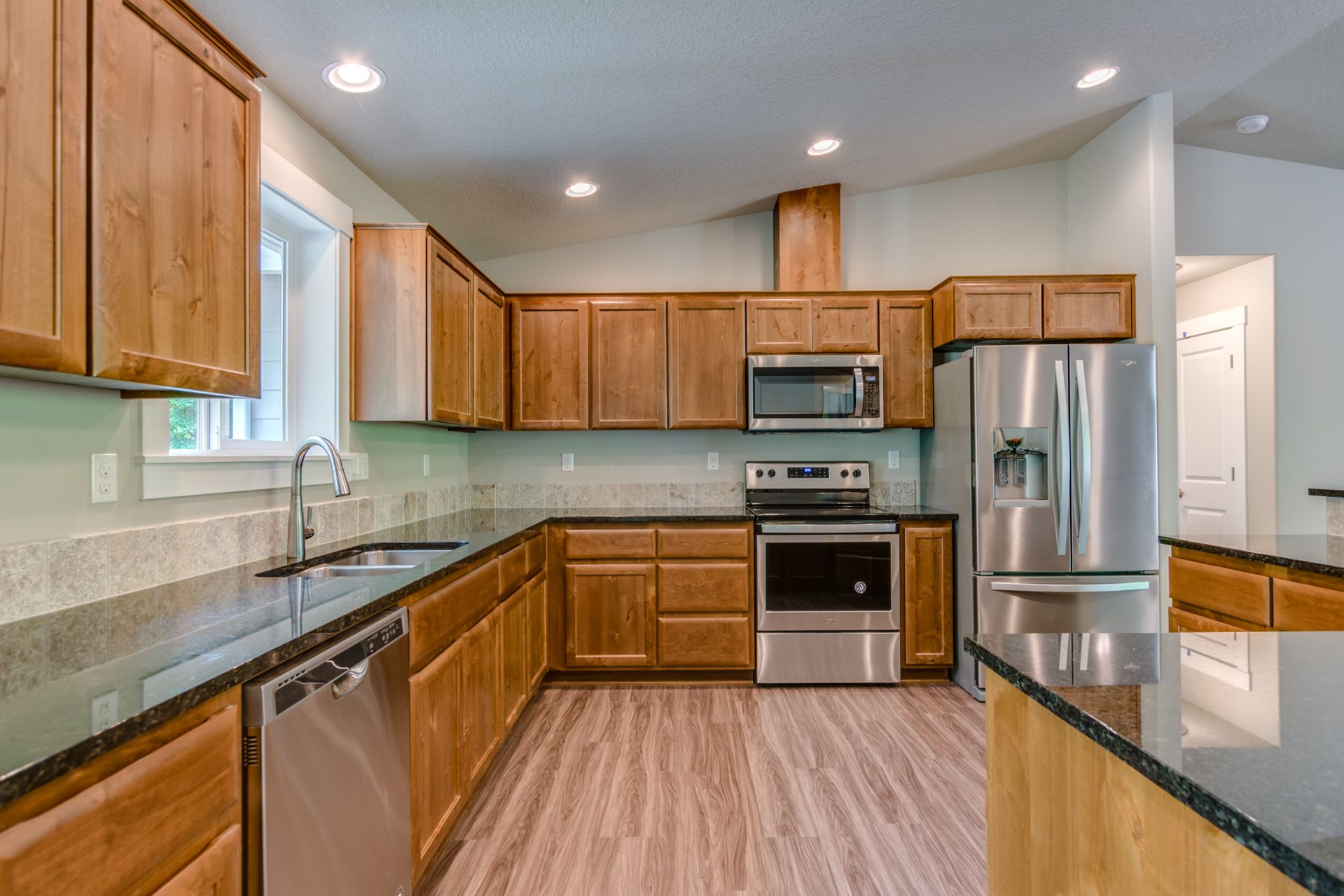 A kitchen with wooden cabinets , stainless steel appliances , and granite counter tops.