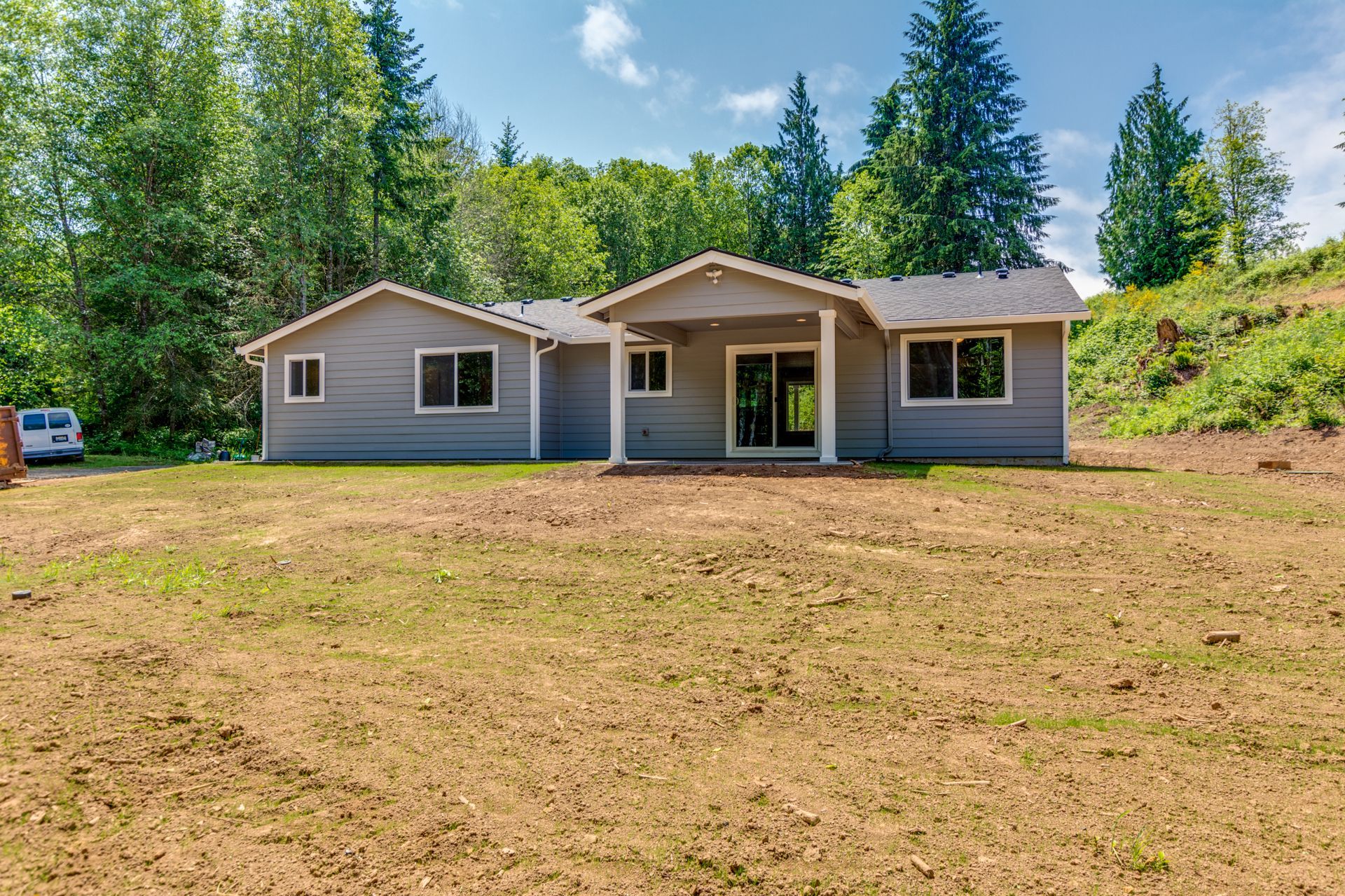 A house is sitting in the middle of a grassy field surrounded by trees.