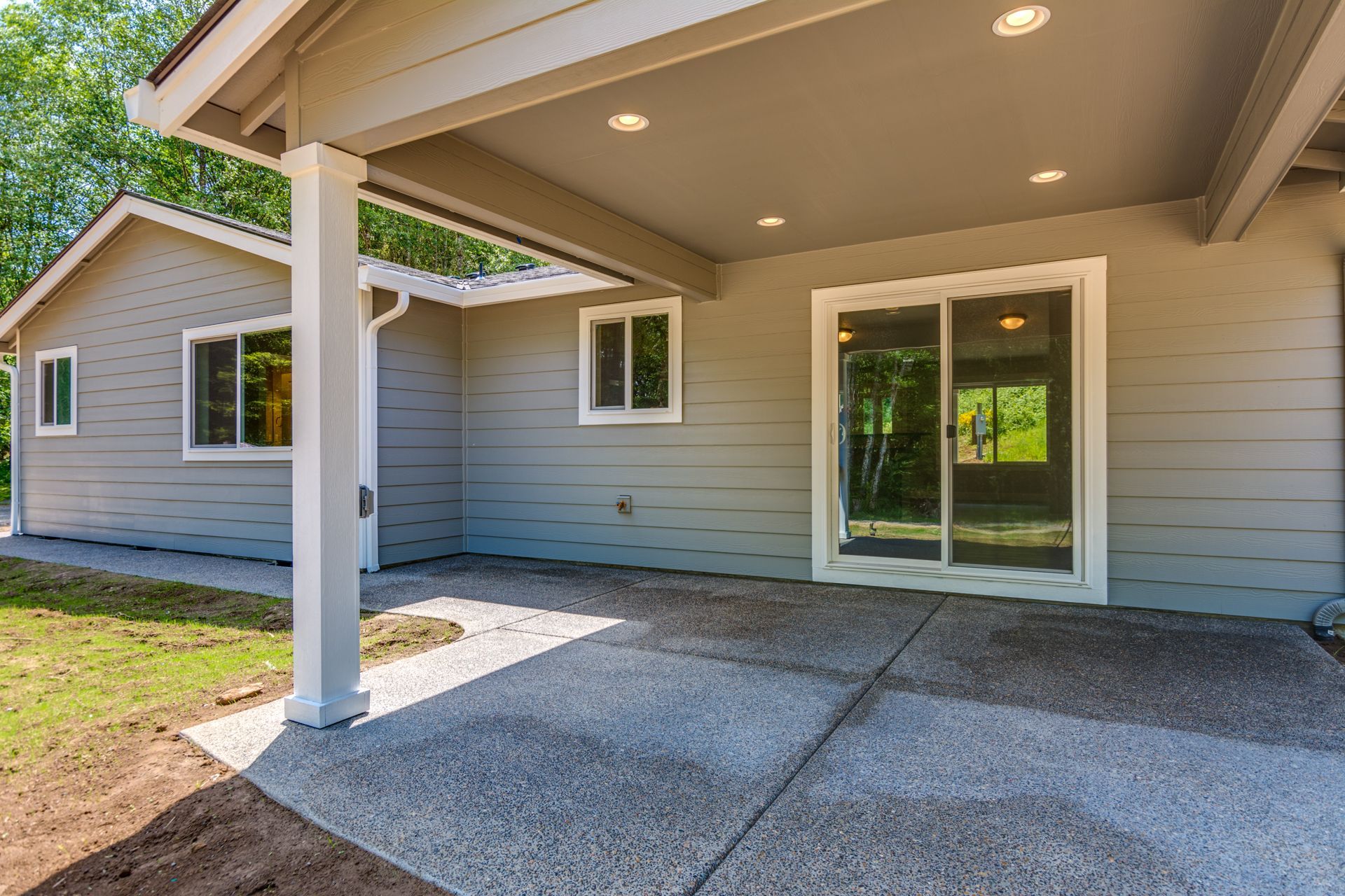 The back of a house with a covered patio and sliding glass doors.