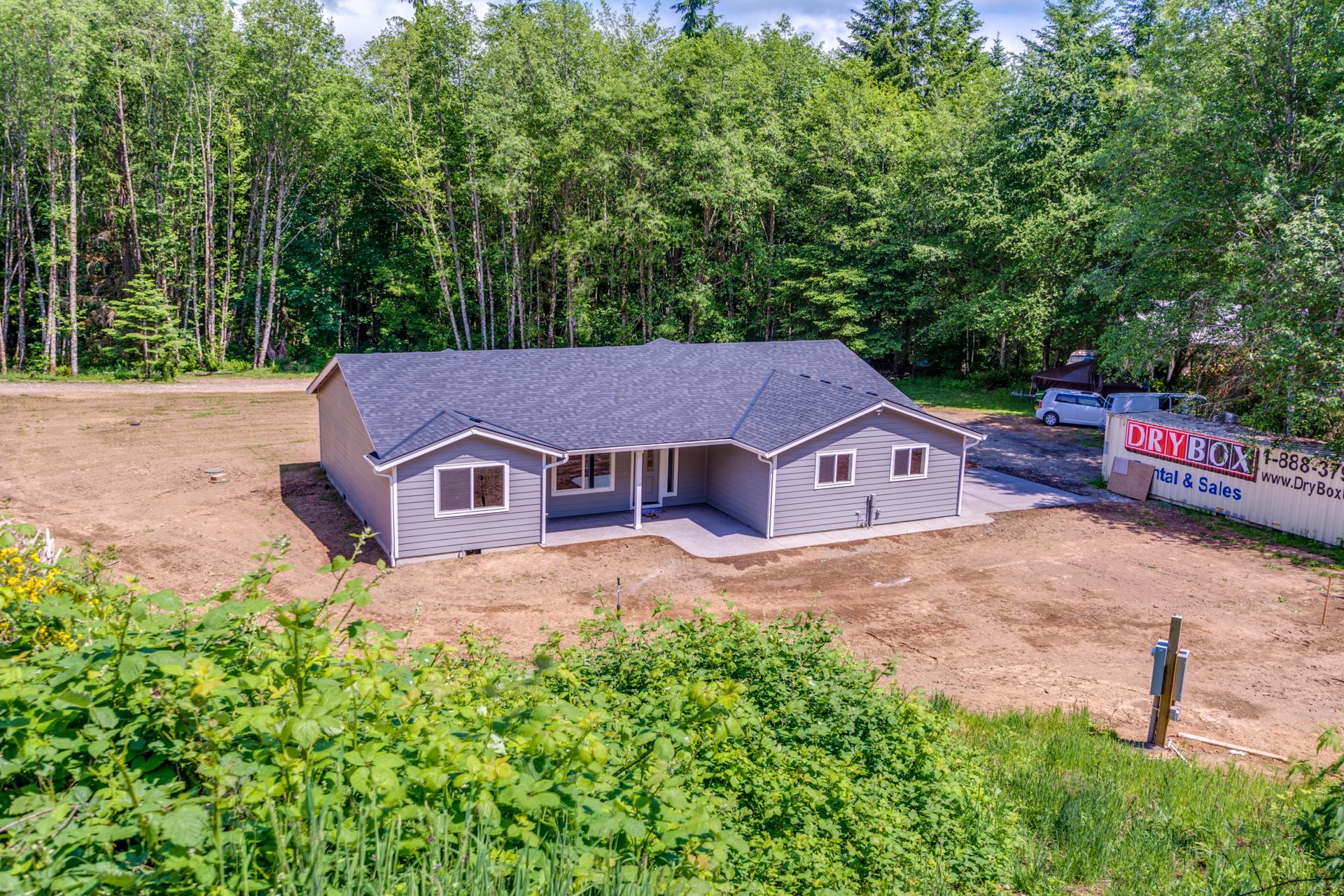 An aerial view of a house in the middle of a field surrounded by trees.
