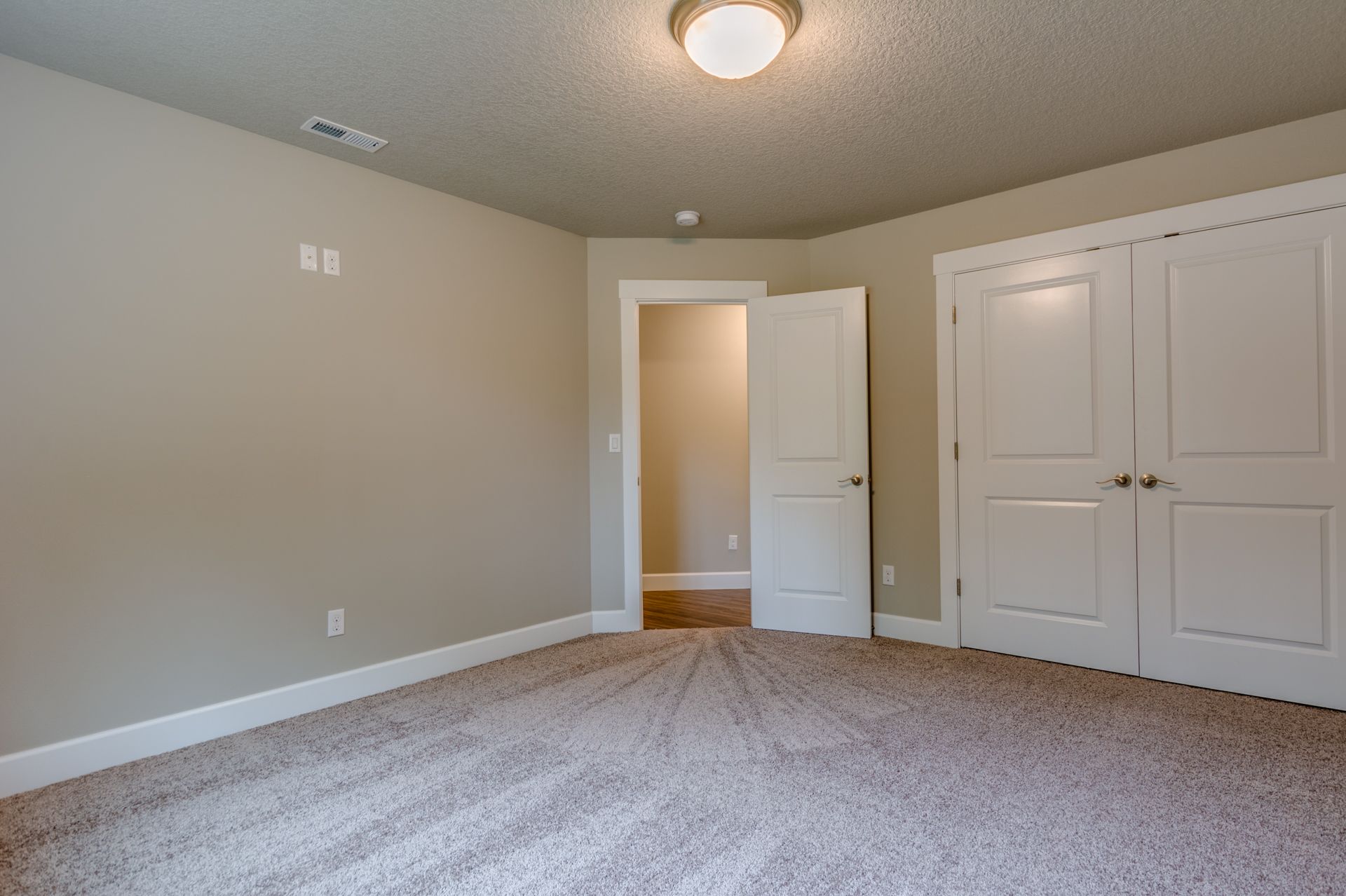An empty bedroom with a carpeted floor and a closet.