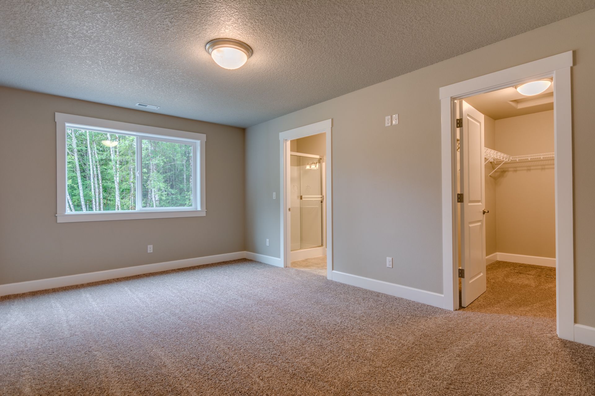 An empty bedroom with a walk in closet and a window.