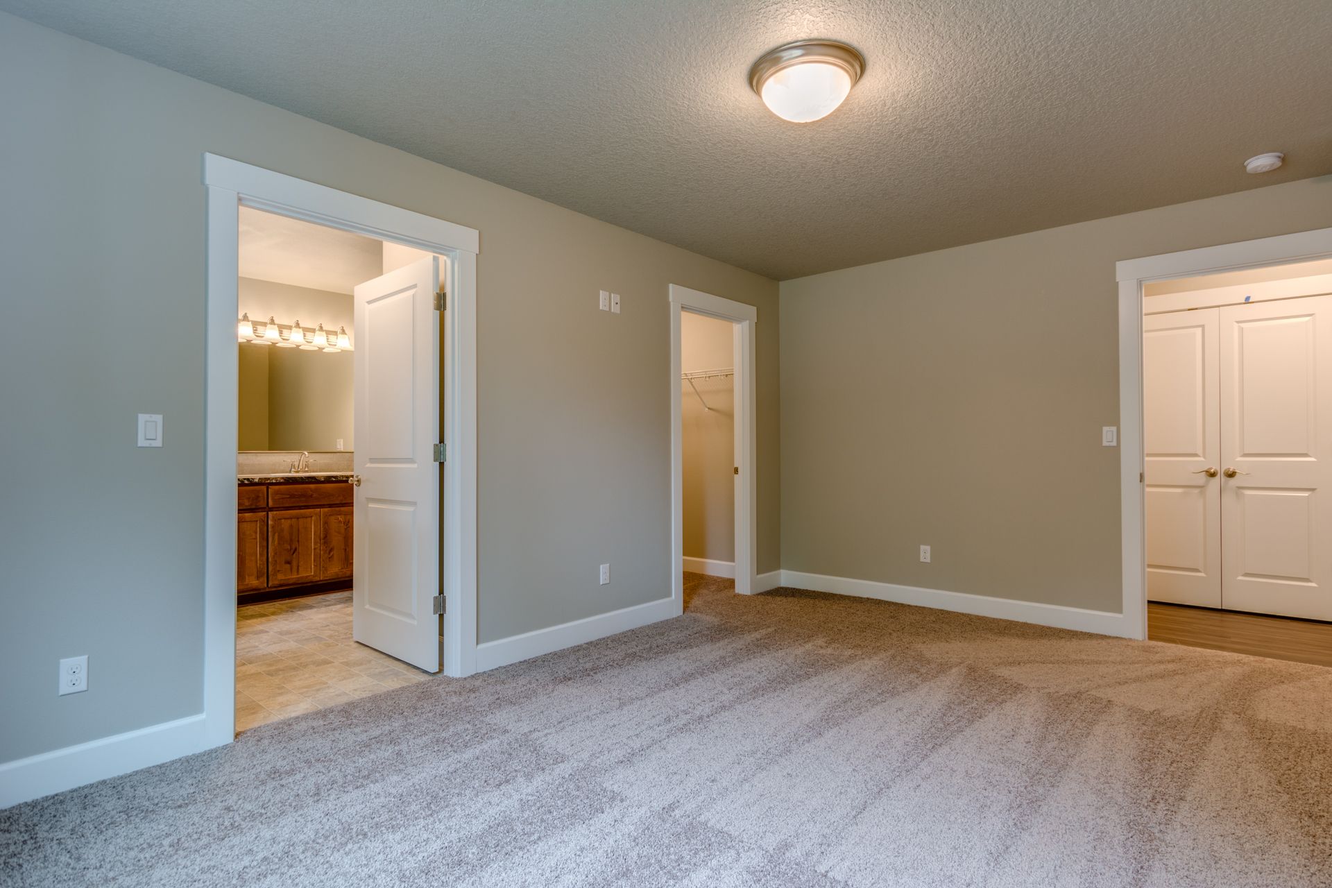 An empty bedroom with a carpeted floor and a bathroom.