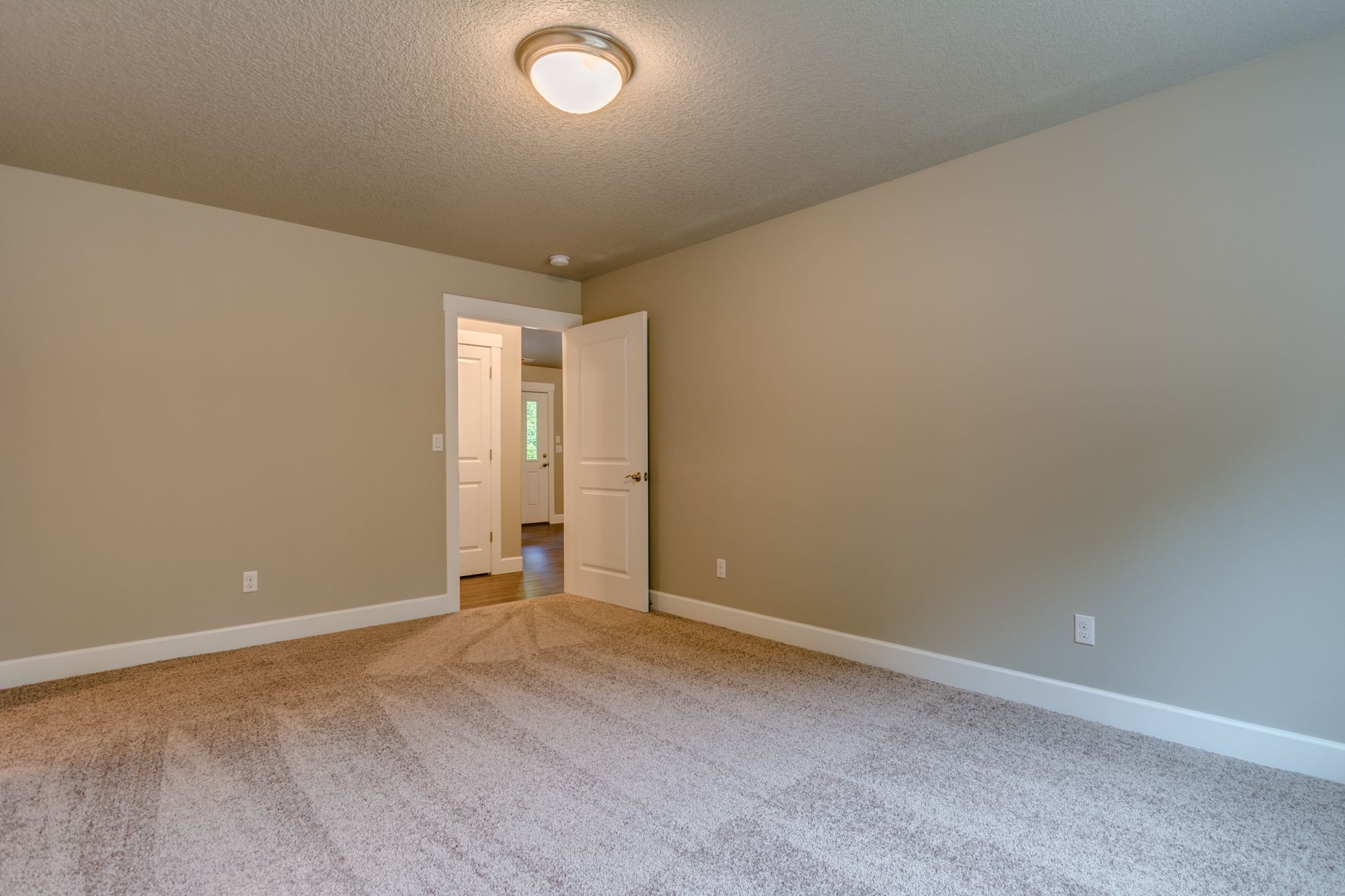 An empty bedroom with a carpeted floor and a ceiling light.