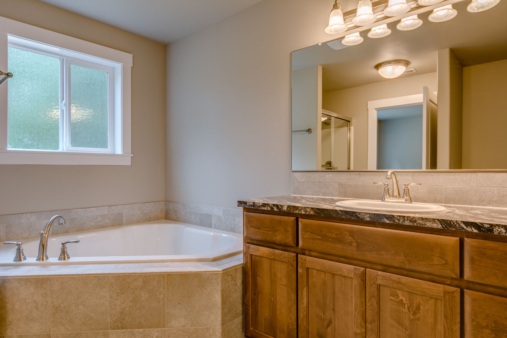A bathroom with a tub , sink , mirror and window.