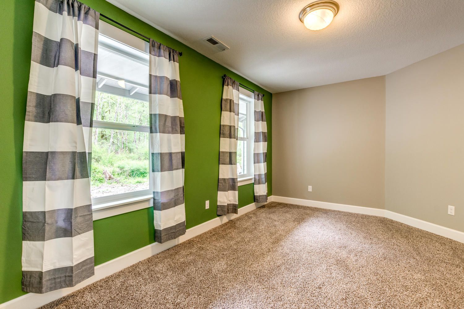 An empty room with green walls and striped curtains.