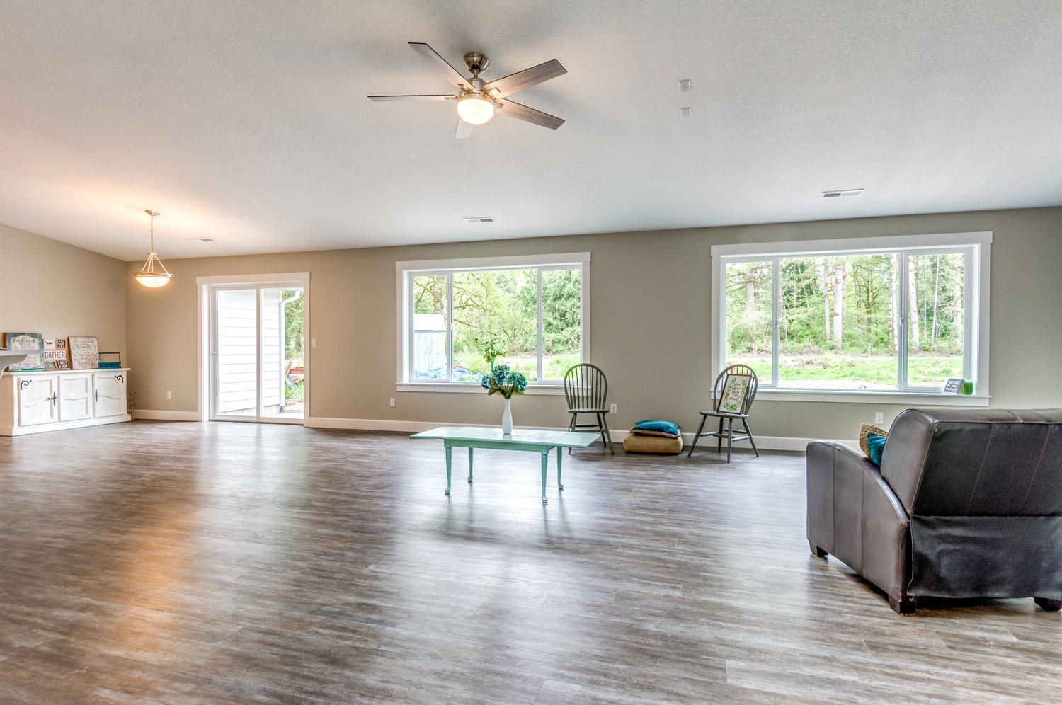 A living room with a couch , chairs , table and ceiling fan.