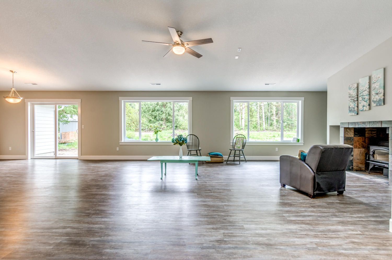 A living room with a ceiling fan , chairs , a table and a fireplace.