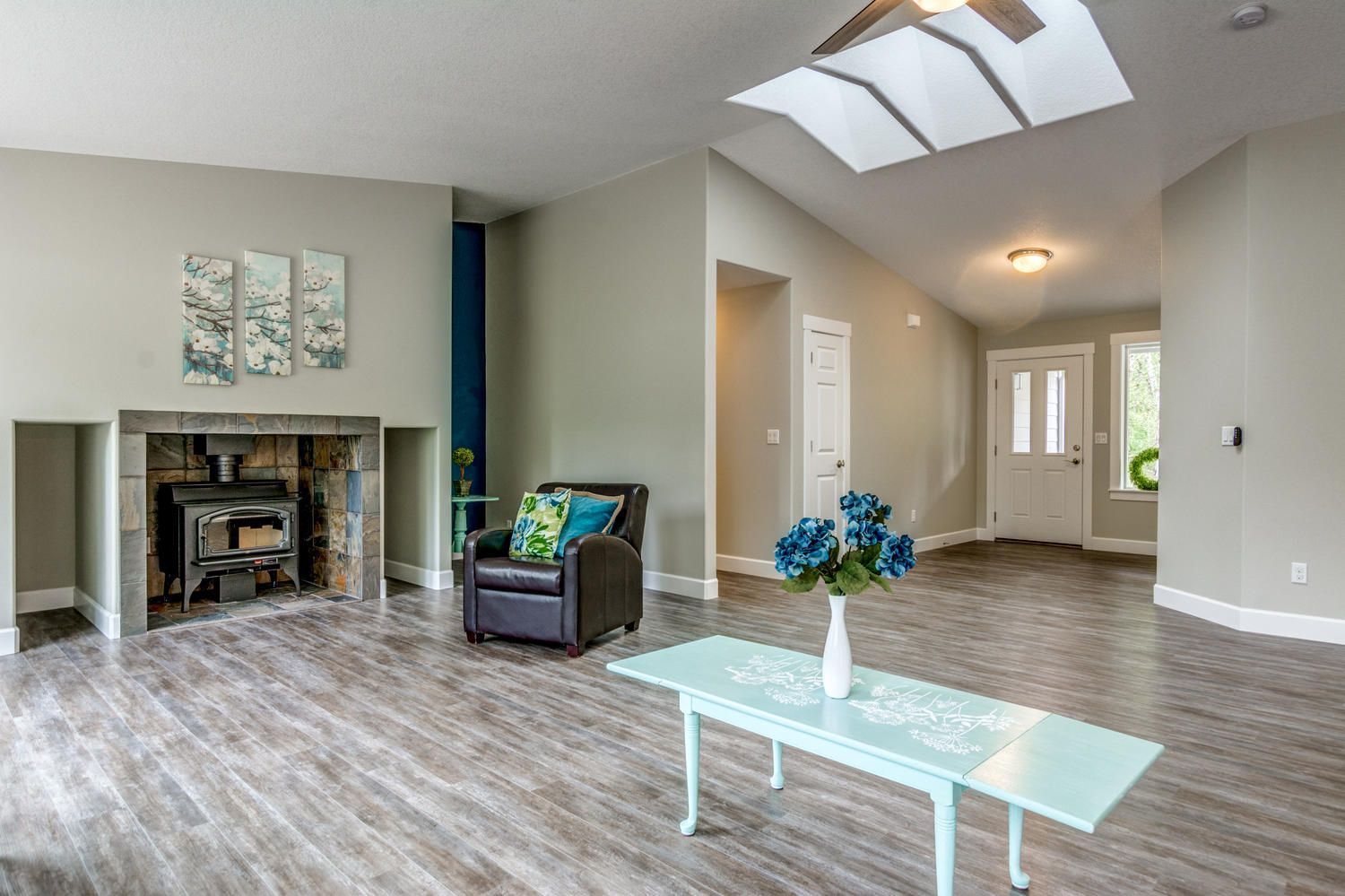 A living room with a table , chair , fireplace and skylight.