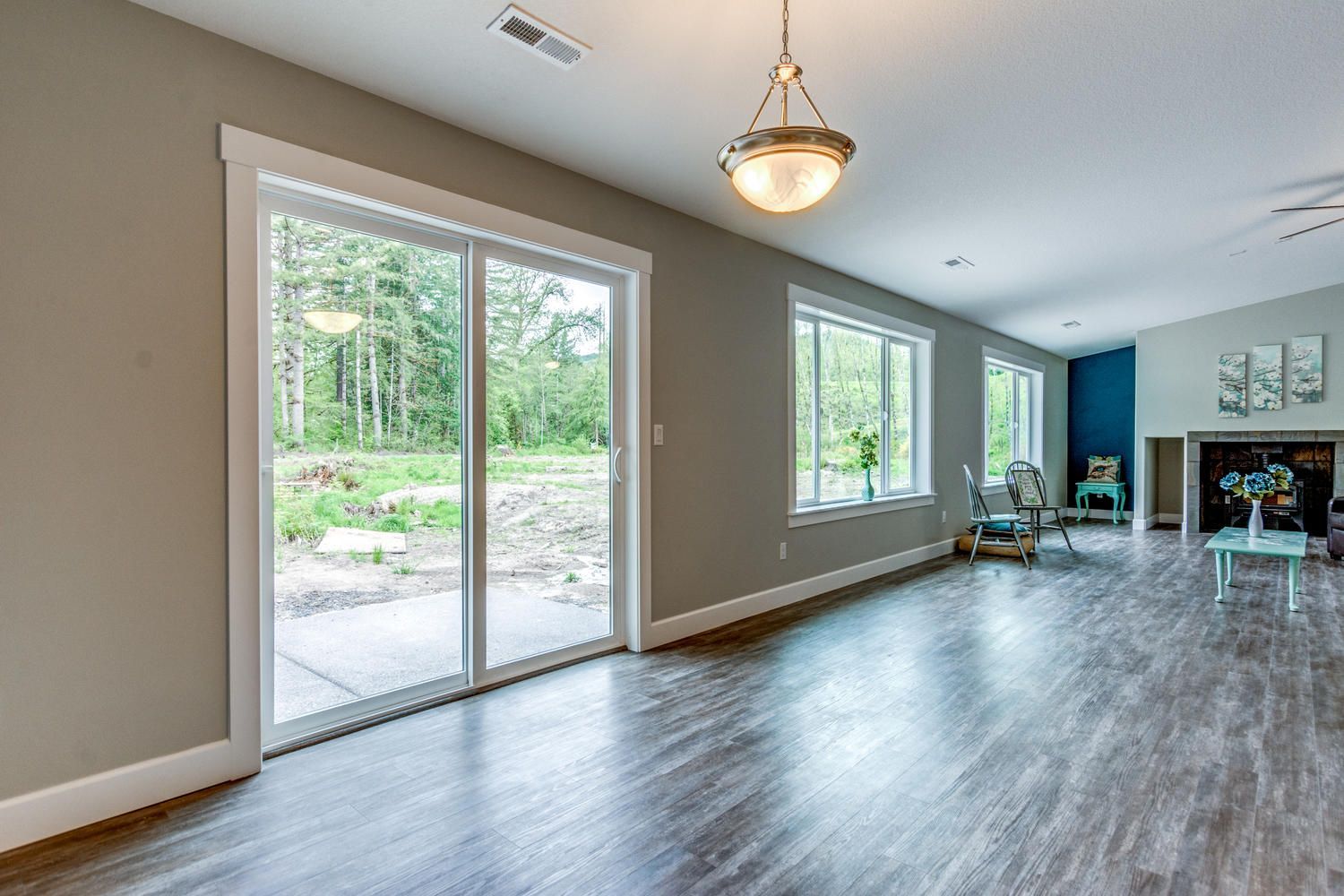 An empty living room with hardwood floors and sliding glass doors.