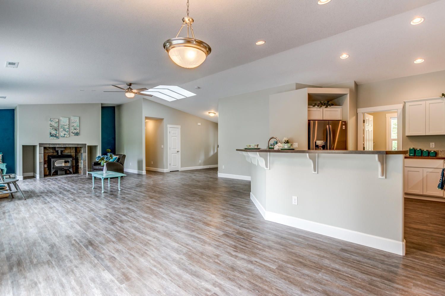A living room and kitchen in a house with hardwood floors and a ceiling fan.