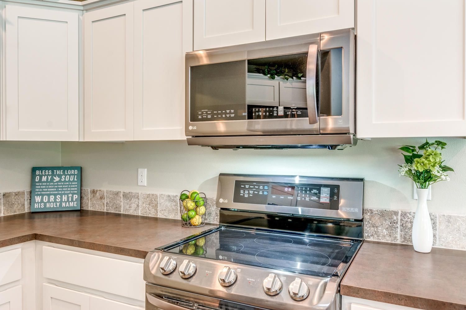 A kitchen with a stove , microwave , and white cabinets.