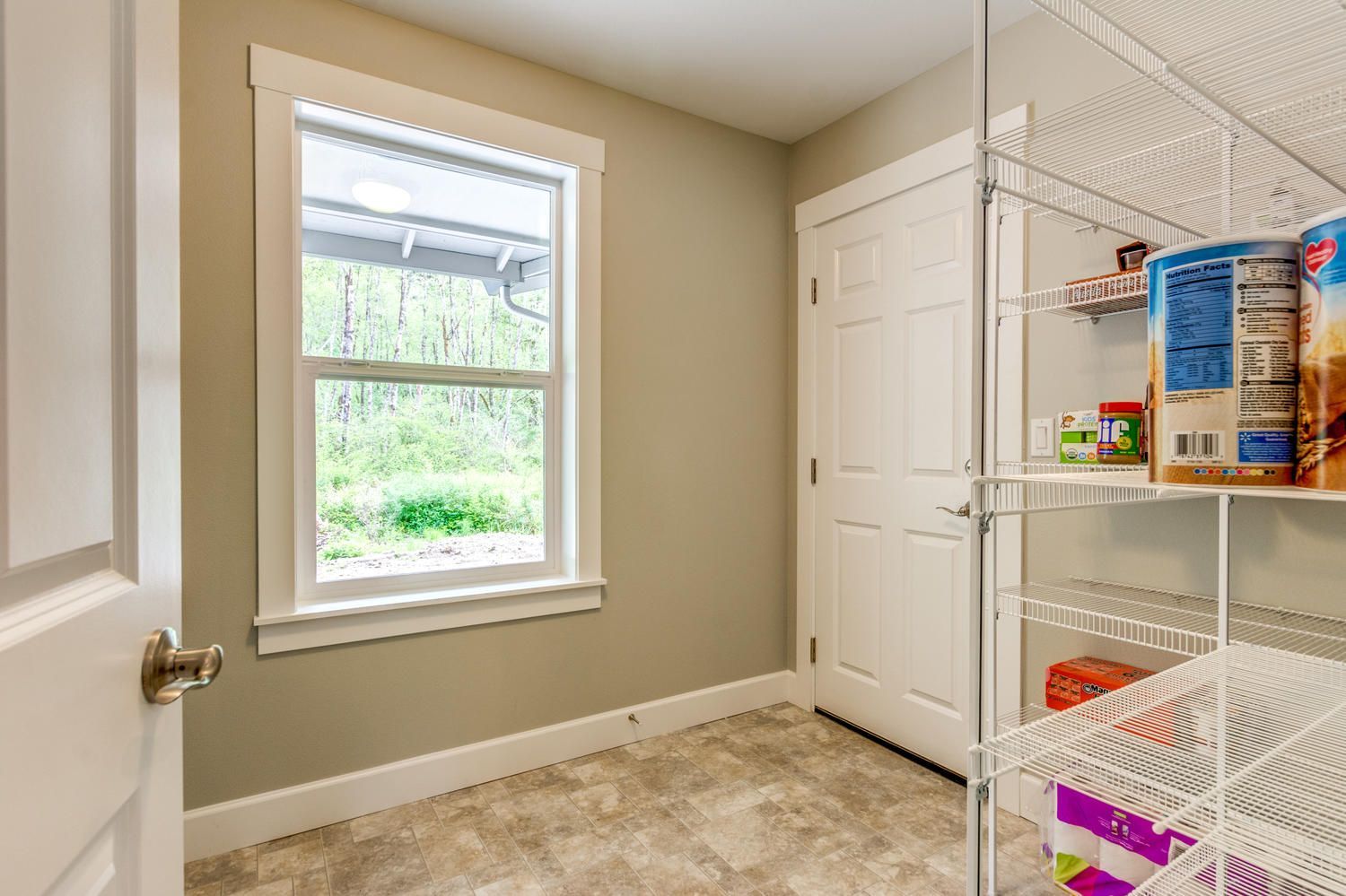 A room with a window and shelves filled with food.