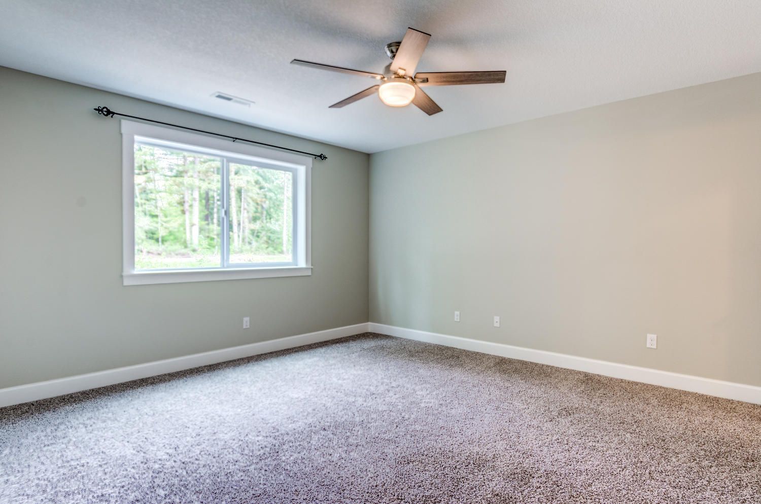 An empty bedroom with a ceiling fan and a window.
