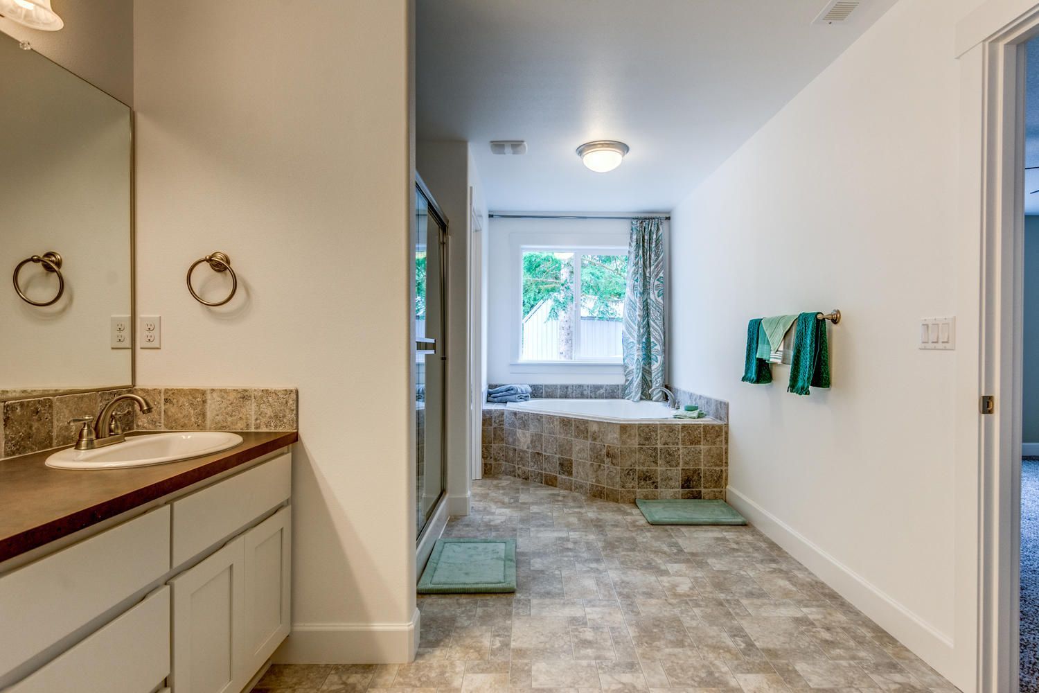 A bathroom with a sink , tub and mirror.