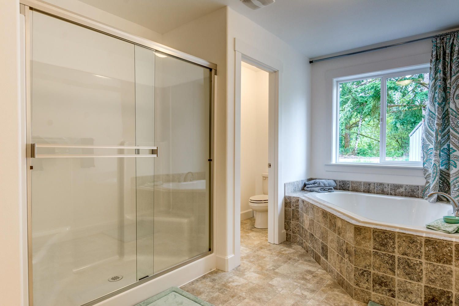 A bathroom with a tub , shower , toilet and window.