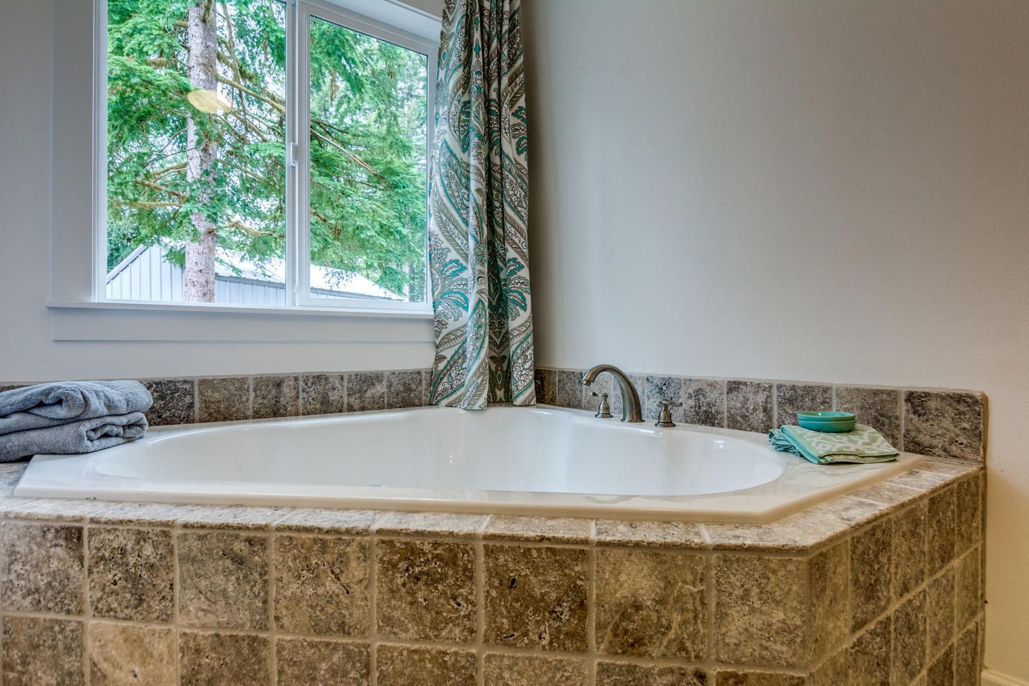 A bathtub in a bathroom next to a window.