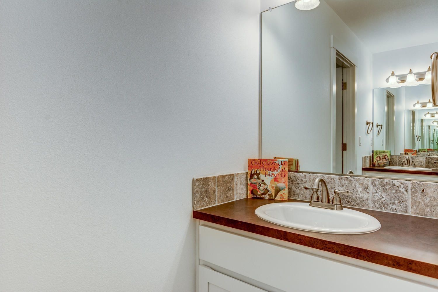A bathroom with a sink , mirror , and cabinets.