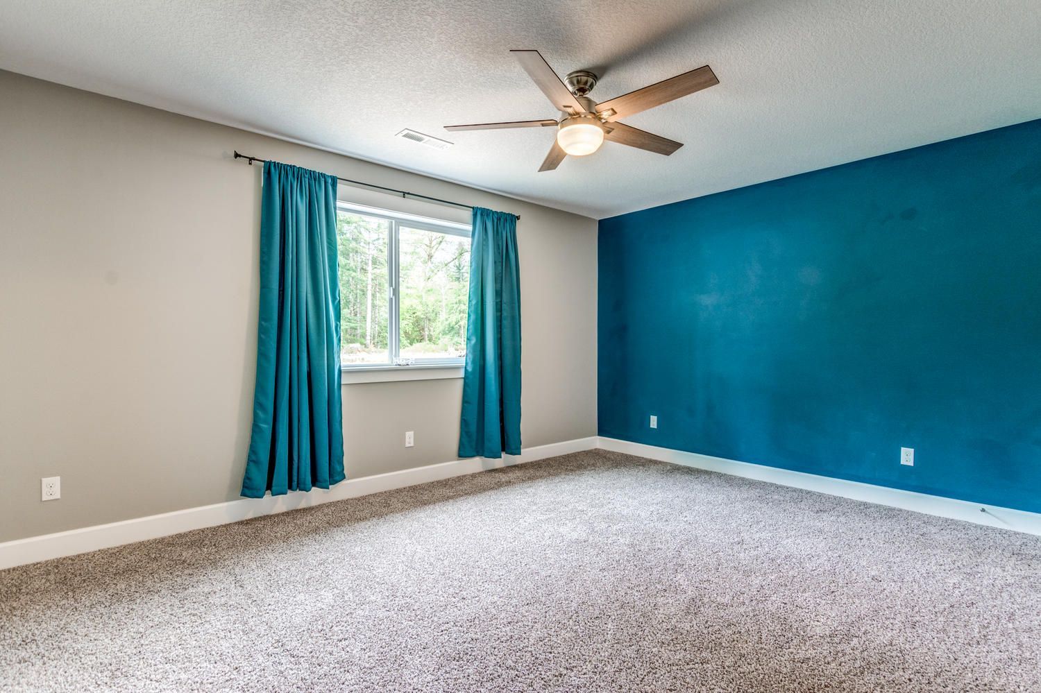 An empty bedroom with blue walls and a ceiling fan.