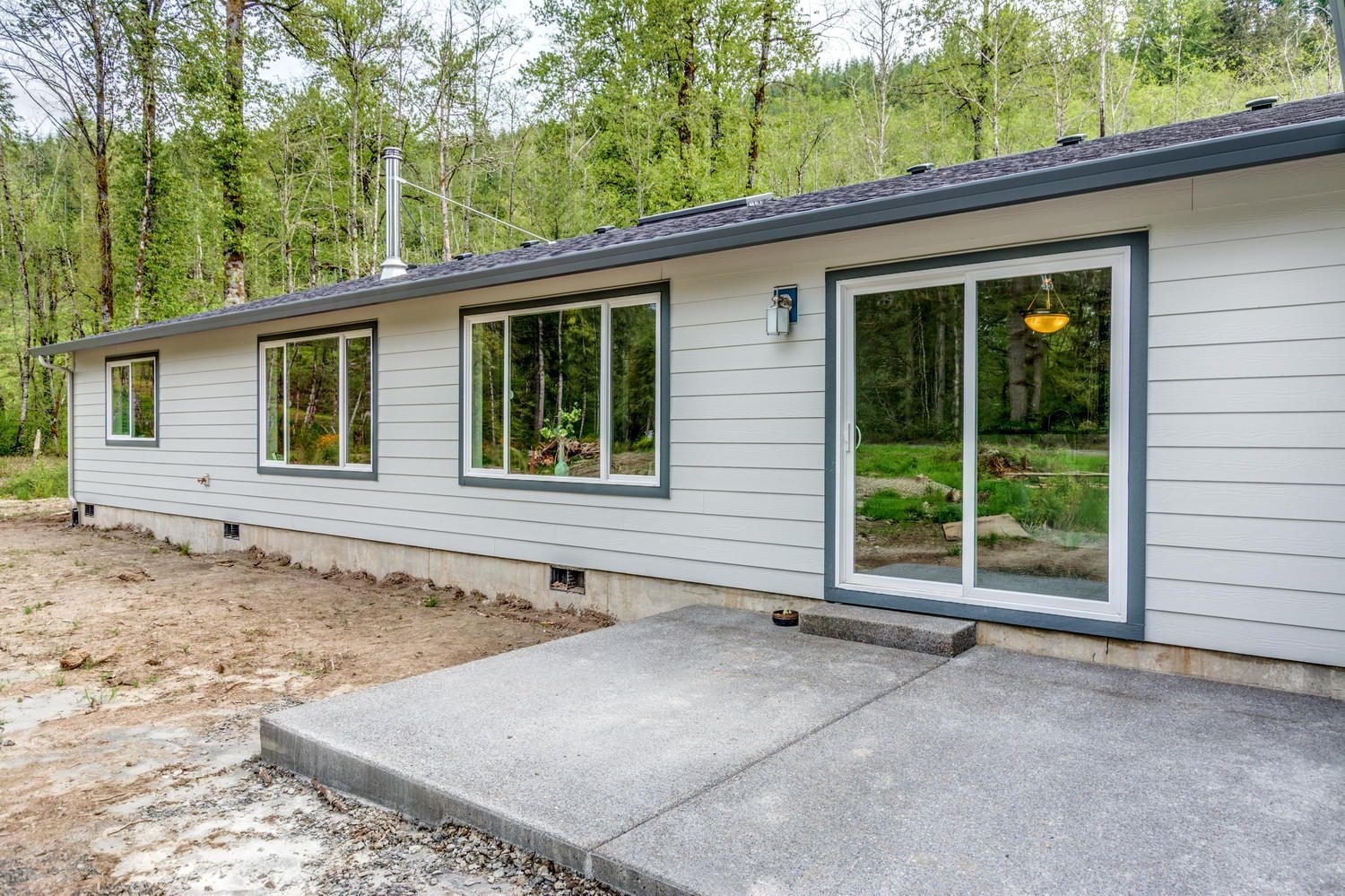 A white house with a lot of windows and a concrete patio in front of it.