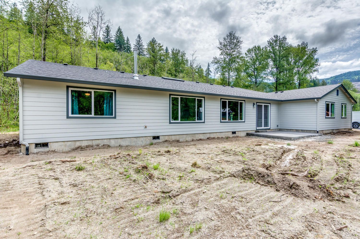 A large white house with a lot of windows is sitting in the middle of a dirt field.