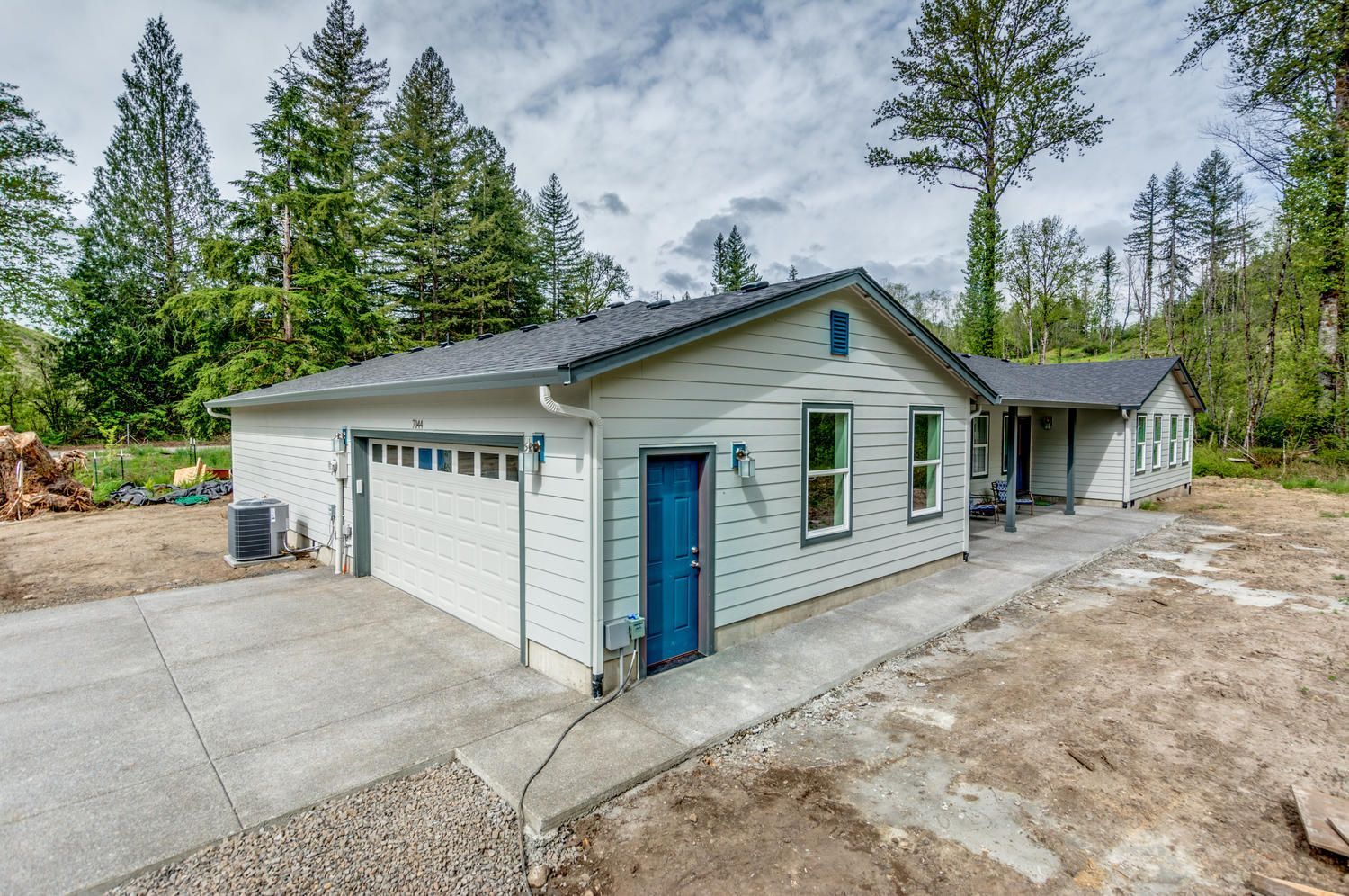 A white house with a blue door is surrounded by trees.