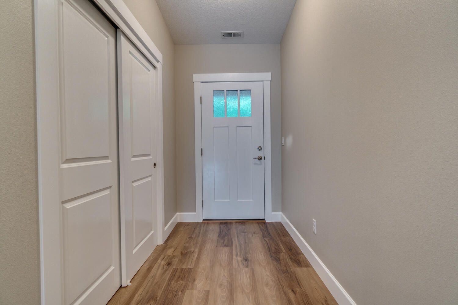 A hallway with hardwood floors and a white door.